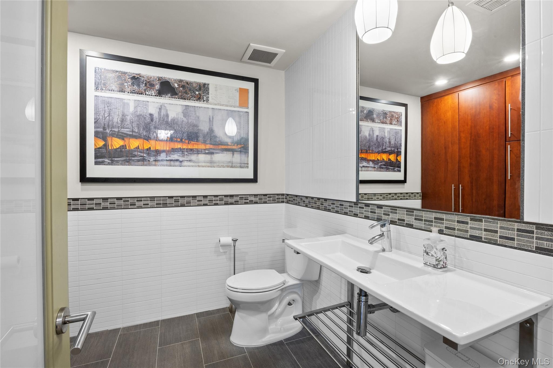 Powder room off entrance foyer with custom storage cabinetry