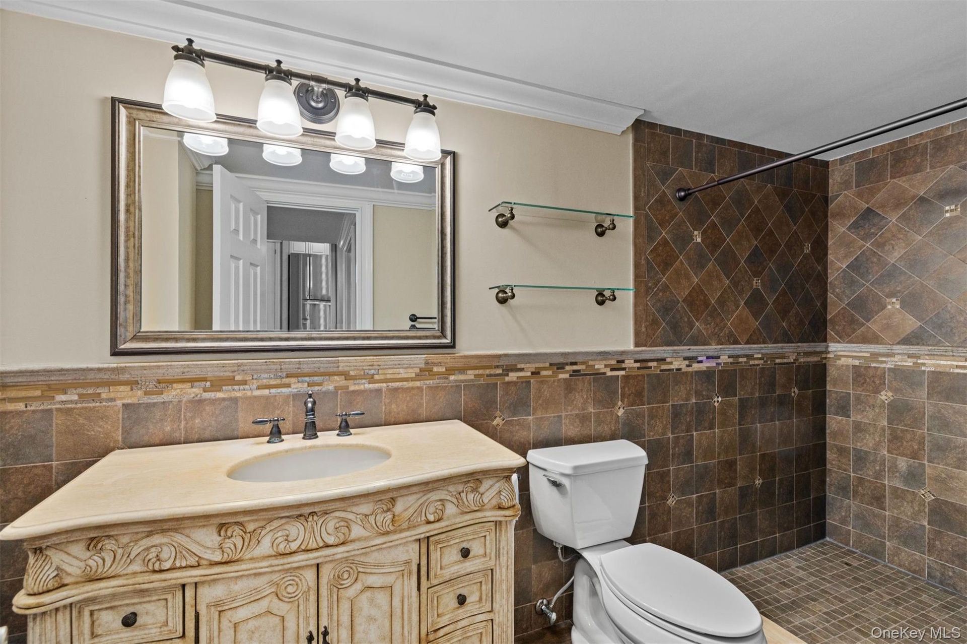 Ornate vanity with integrated sink, bronze-tone faucet, and custom tile backsplash, walk-in shower, crown molding