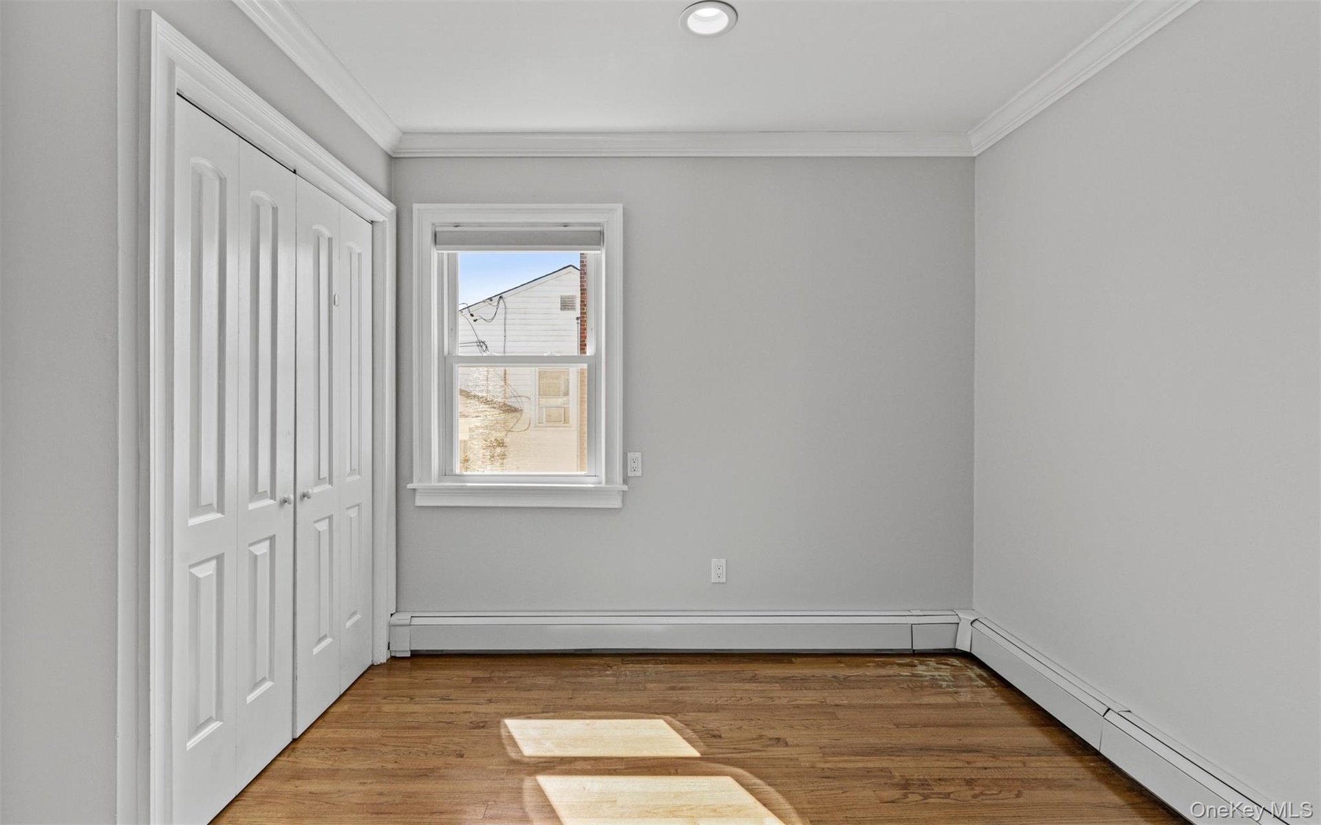 Hardwood flooring, recessed lighting, crown molding, white bi-fold closet doors, and a double-hung window