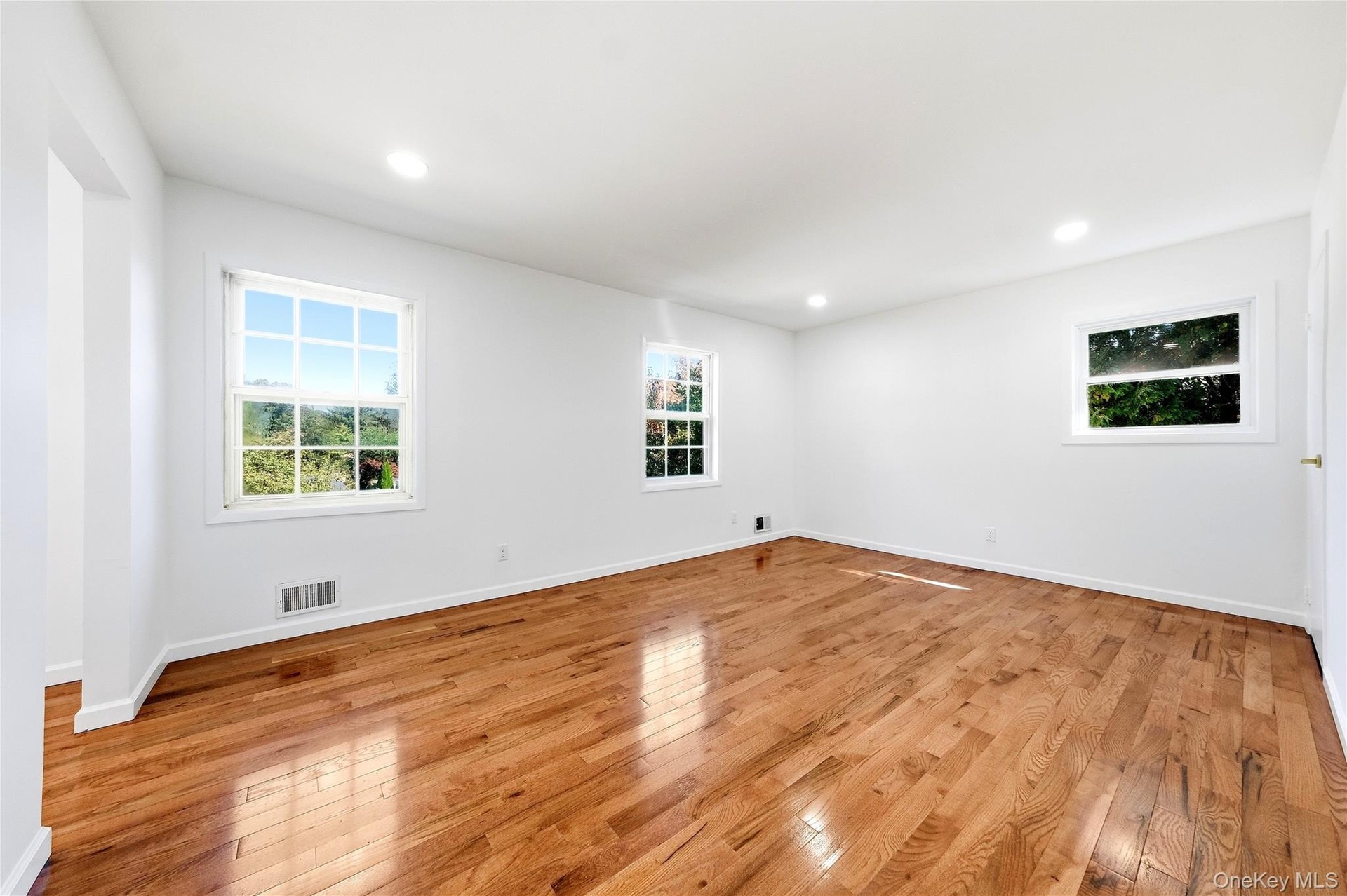 Hardwood flooring, recessed lighting, white walls, and multiple windows