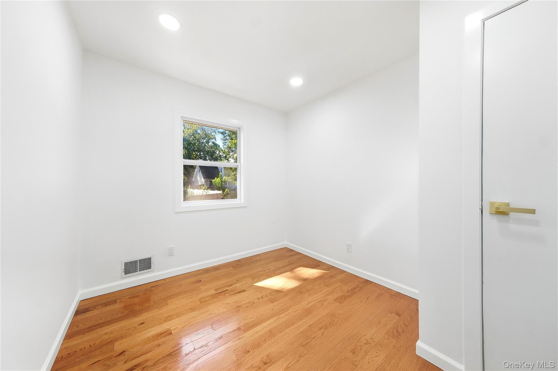 Hardwood flooring, recessed lighting, white interior walls, white trim, and a window with exterior scenery