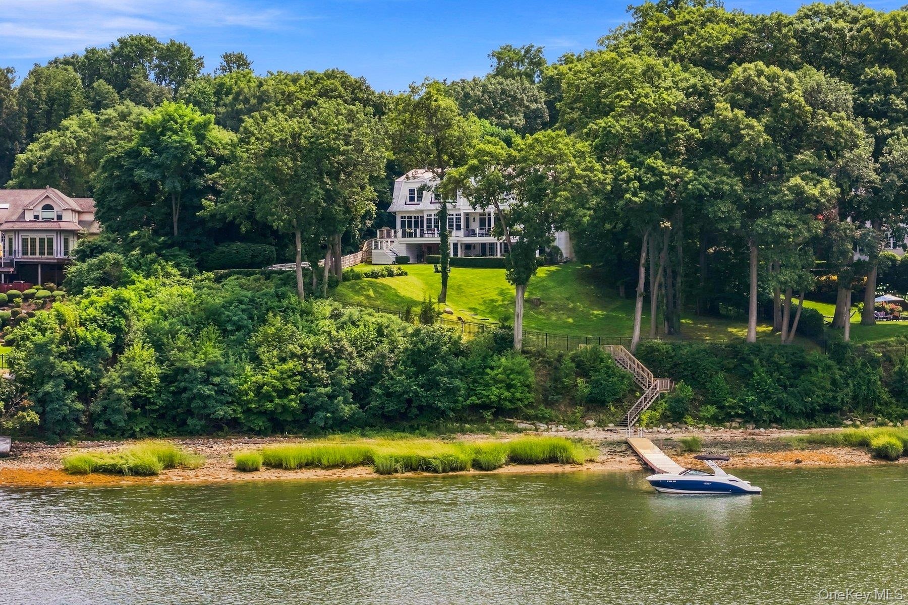 Waterfront property featuring a multi-story residence with expansive deck, a natural shoreline, and a private dock.