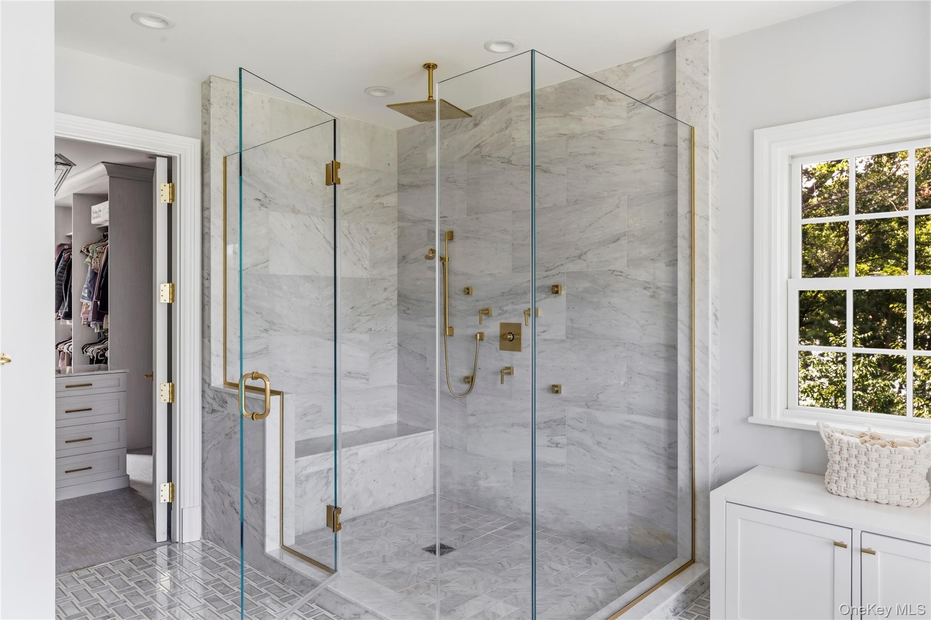 Glass-enclosed shower with marble tile