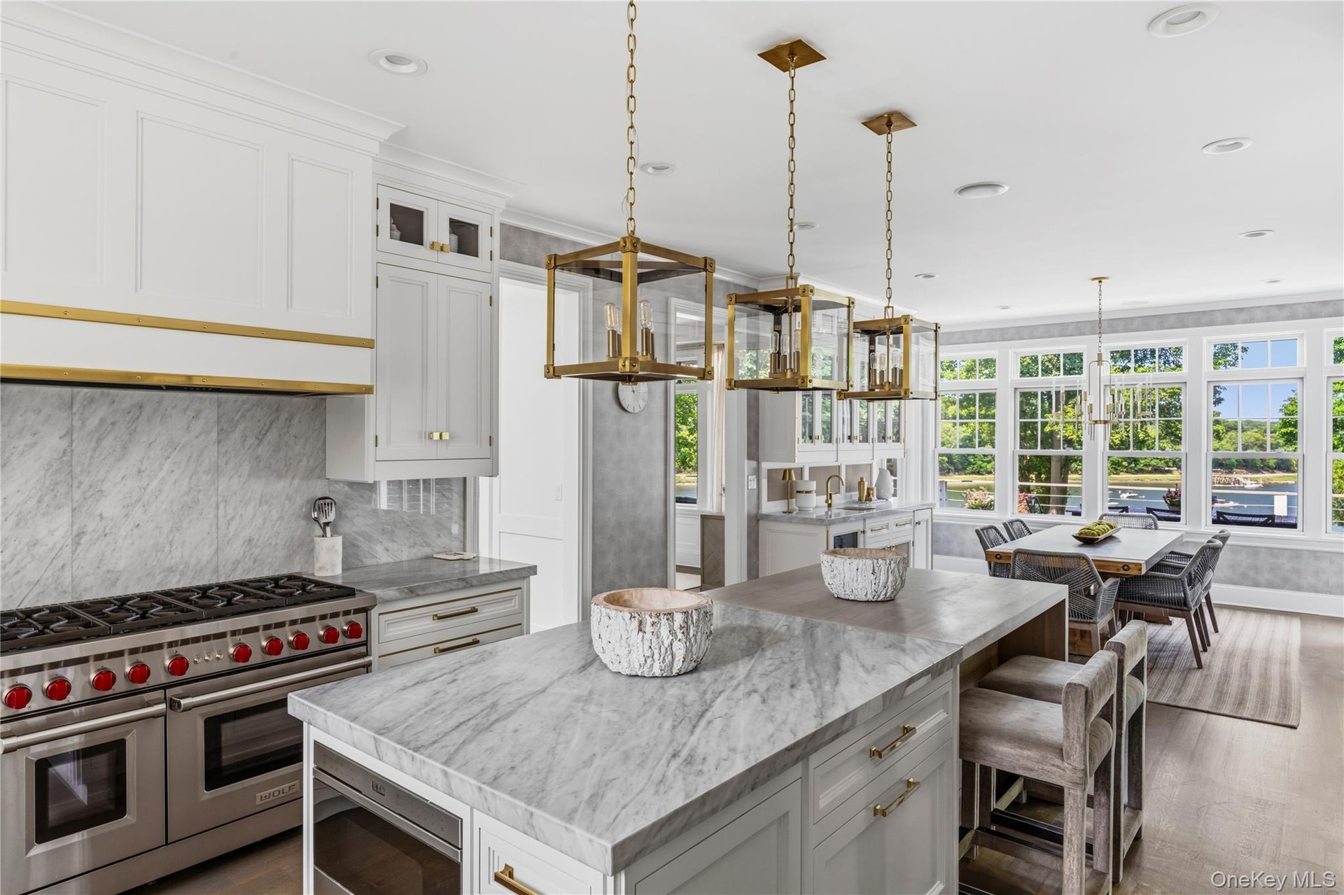 Gourmet kitchen with professional grade stainless steel range, custom cabinetry, large central island with seating, and ample natural light through ex