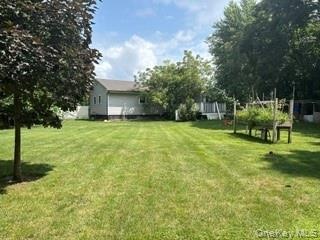 Expansive green lawn with mature trees and a raised garden bed