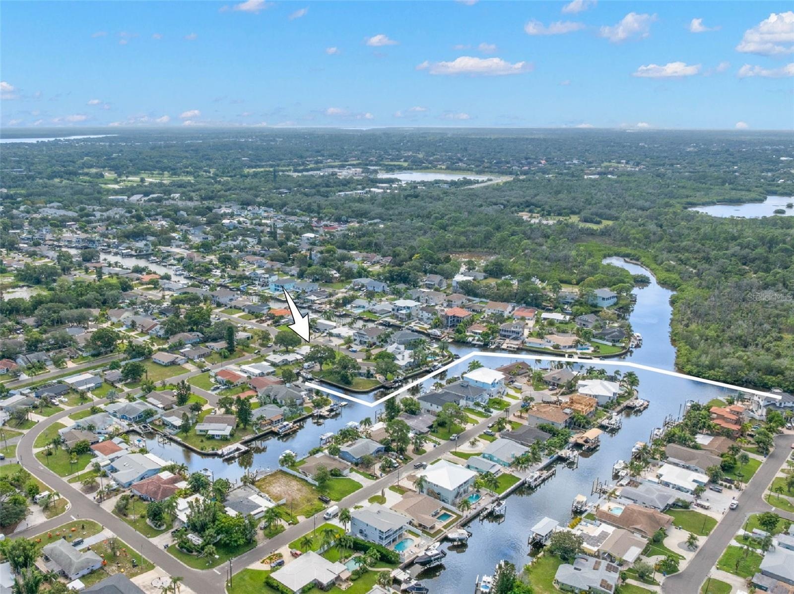 An aerial view showcases Baywood Village’s network of saltwater canals and the home’s close-to-the-water setting, with direct Gulf access from the nei