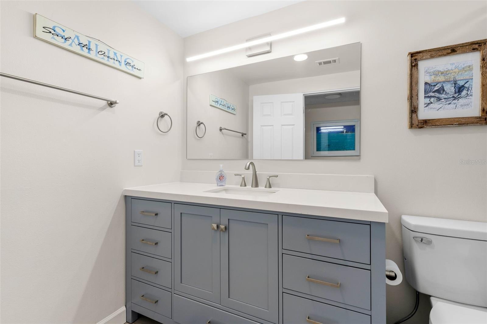 The remodeled primary bath (2025) features a wide gray vanity with abundant drawer storage, a sleek white countertop, oversized mirror, and contempora