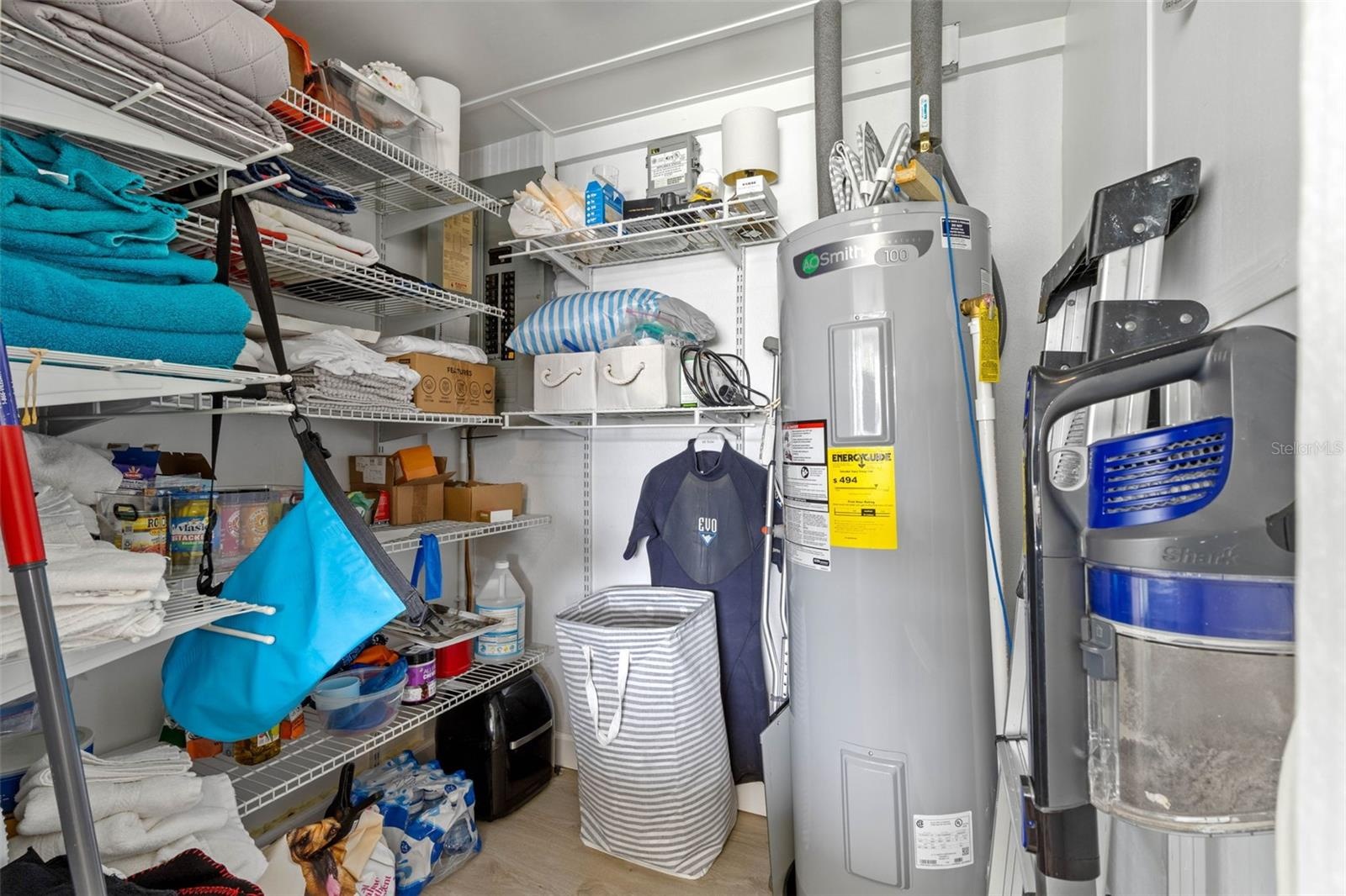 A dedicated utility and storage room keeps household essentials organized with extensive wire shelving and a water heater (2025) tucked neatly to one 