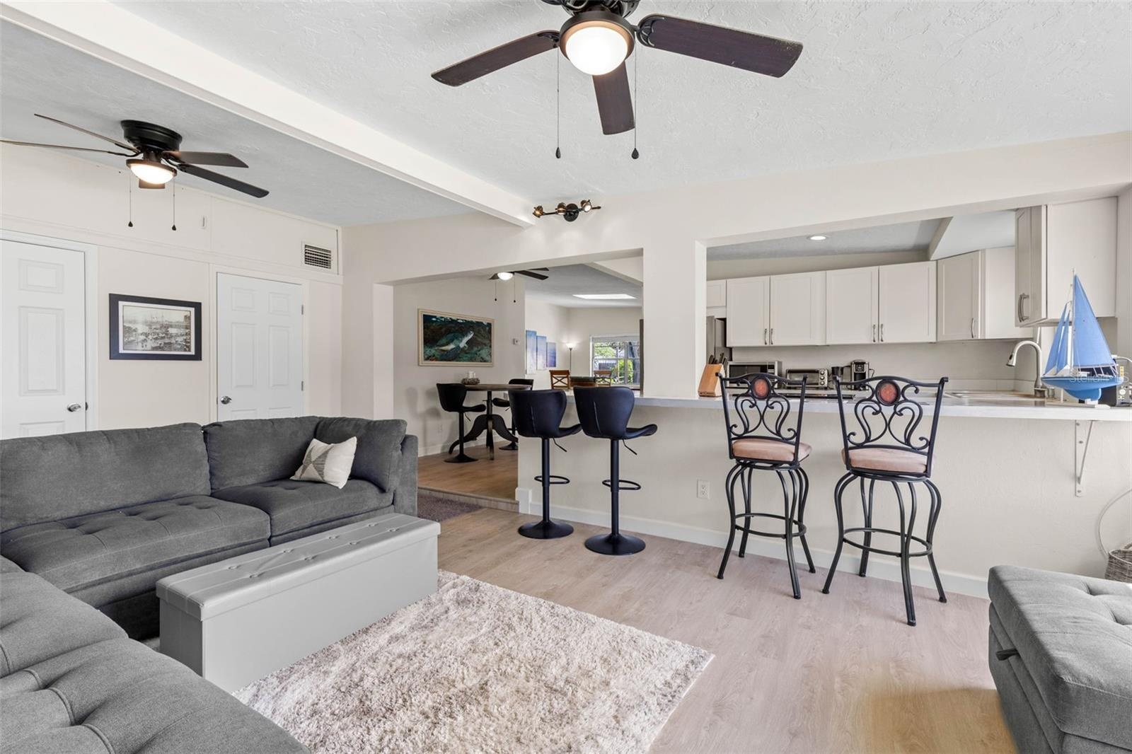 The spacious living area features dual ceiling fans, a soft neutral color palette, and 2025 luxury vinyl plank flooring, with an open connection to th