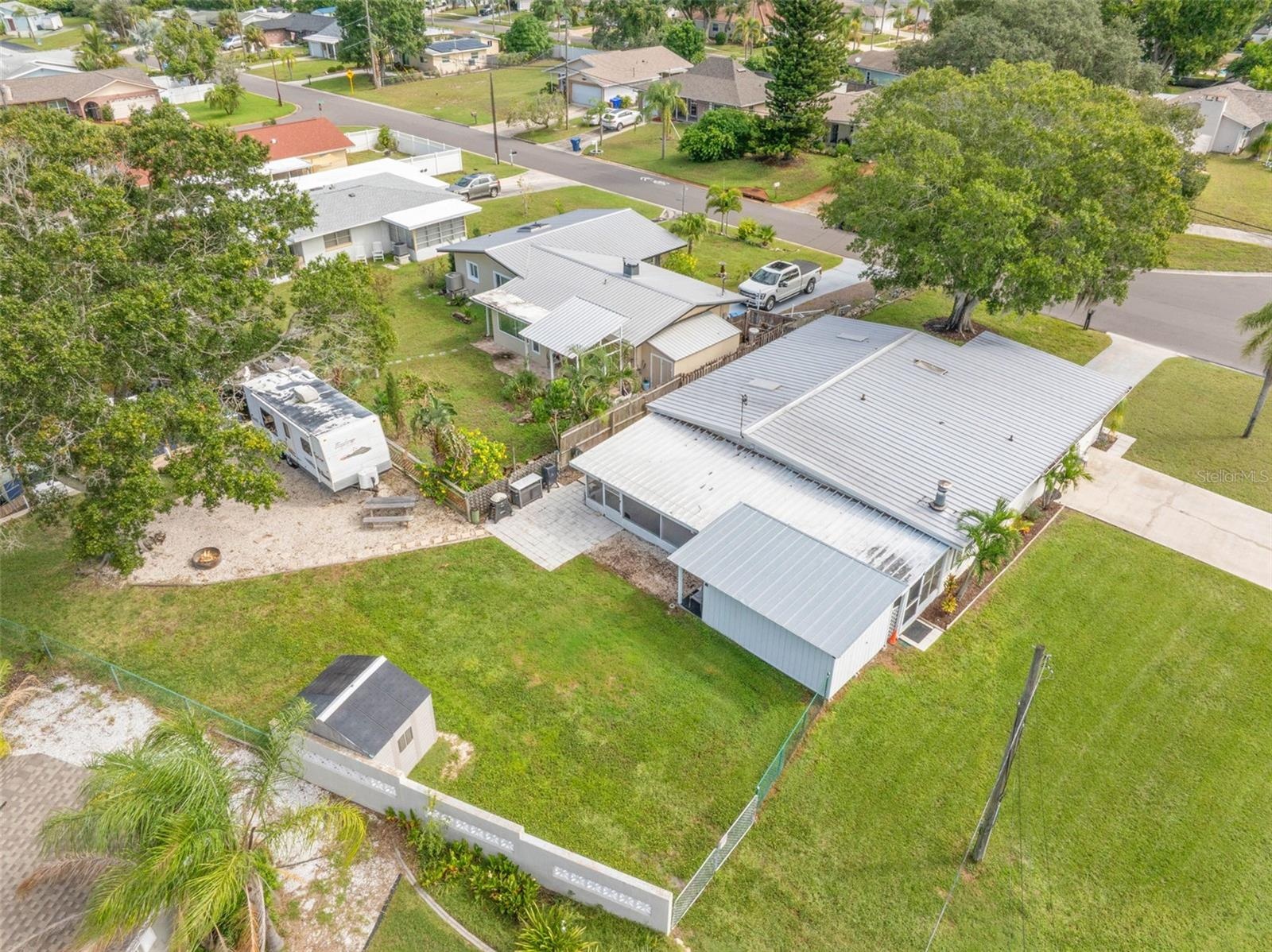 An aerial view shows just how much this property offers, with a broad backyard, RV parking area, screened lanai, workshop/storage space, and plenty of
