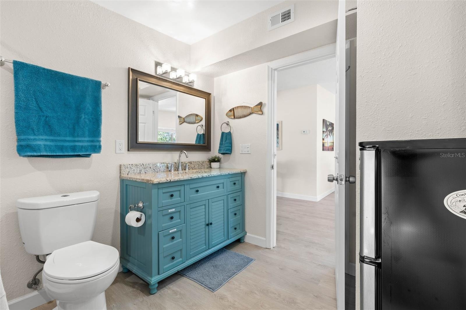 The updated second bath (2019) adds a splash of personality with a turquoise vanity, stone-look countertop, framed mirror, modern lighting, and plenty