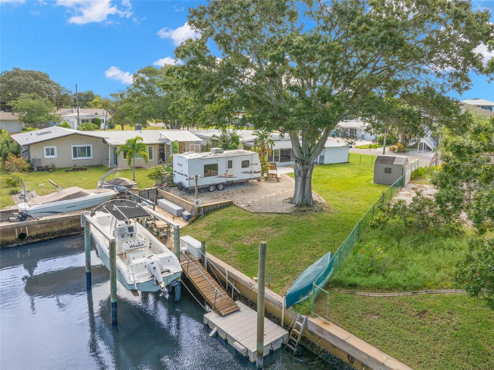 An aerial view showcases the property’s waterfront lifestyle, with a 10,000-pound boat lift, wooden dock and floating dock along the canal, plus gener