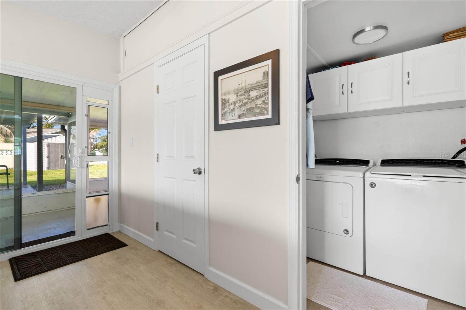 A dedicated laundry room keeps everyday chores tucked neatly away, with a full-size washer and dryer, overhead cabinetry for storage, and convenient a