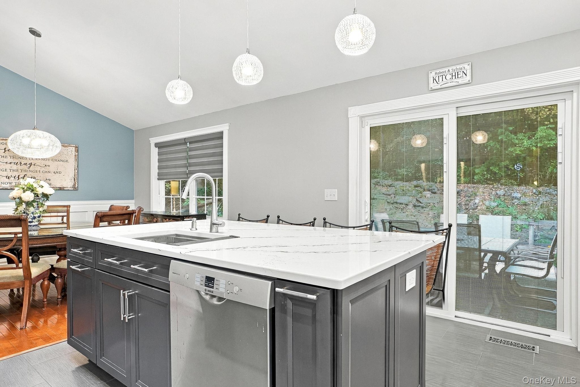 Kitchen island with white-veined countertop, integrated sink, and stainless steel dishwasher
