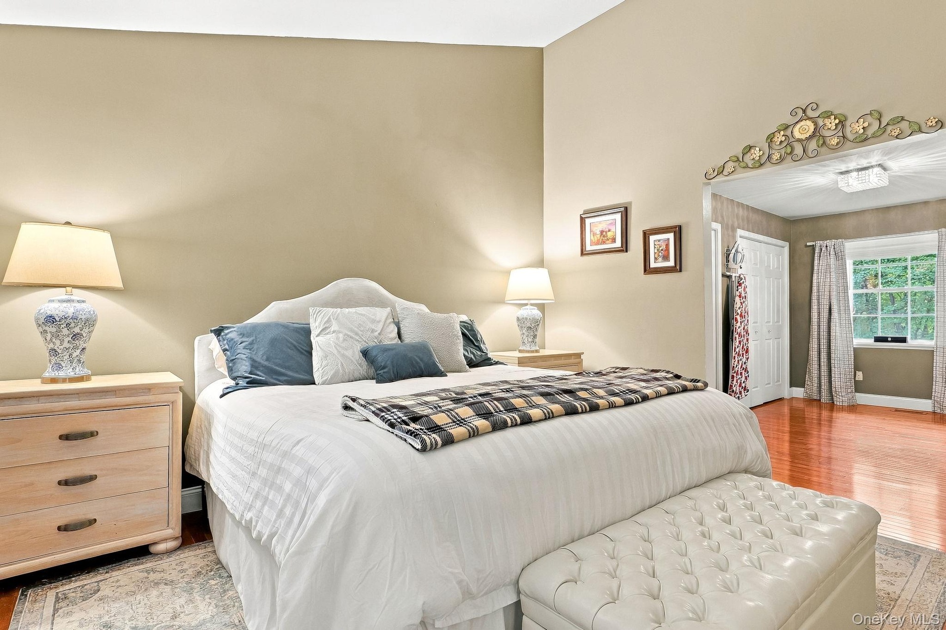 Vaulted ceiling with light-toned walls, rich wood-finish flooring, and a decorative archway
