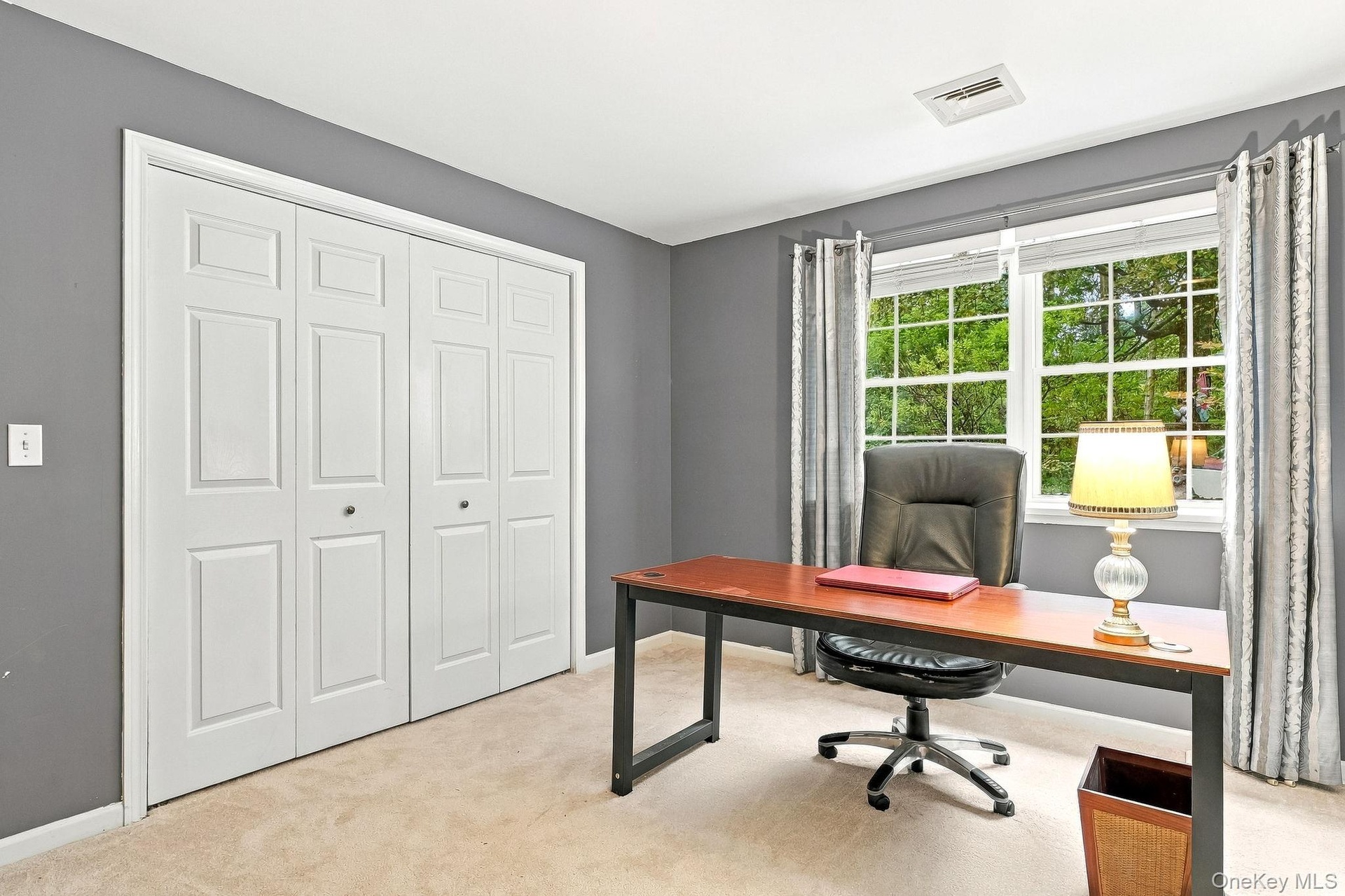 Double-panel closet doors, two large windows, wall-to-wall carpeting, and neutral wall paint