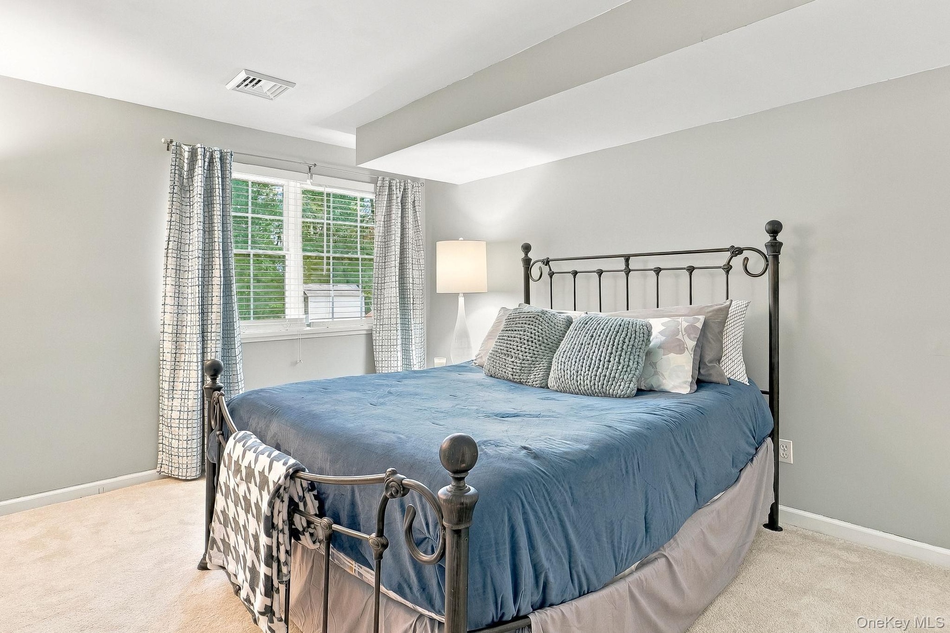 Carpeted room with light gray walls, a window featuring horizontal blinds, and a built-in recessed ceiling