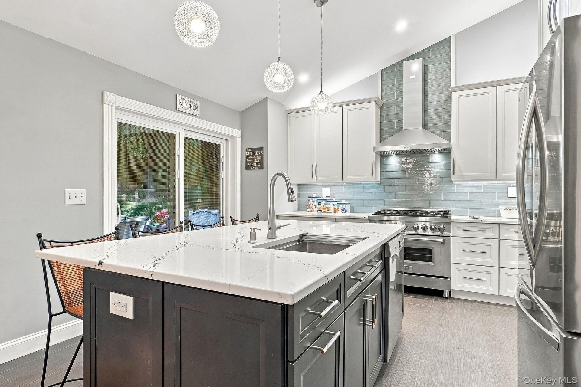 Gourmet kitchen featuring a center island with sink, white countertops, built-in stainless steel appliances, and light wood-finish flooring