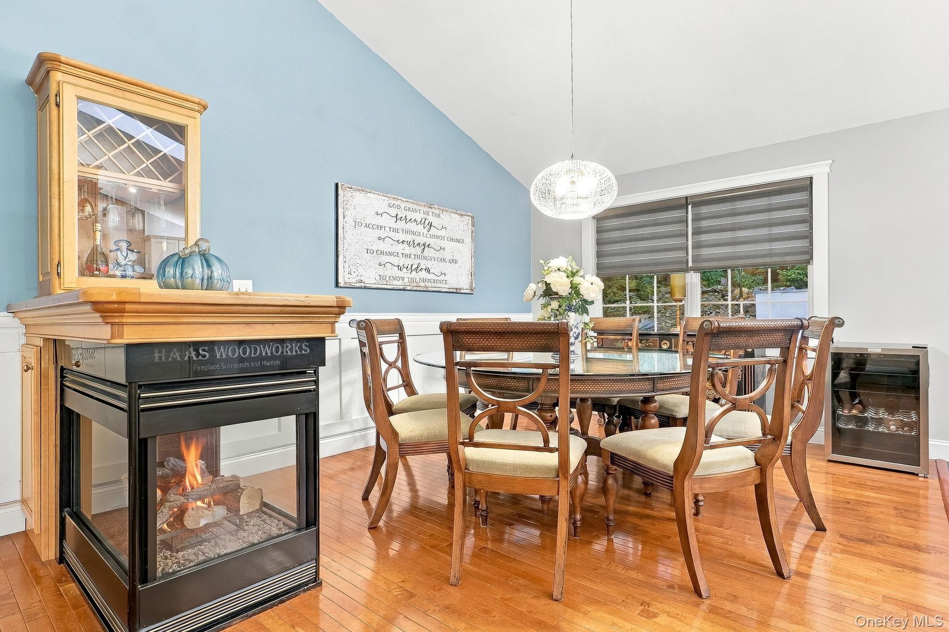 Vaulted ceiling, hardwood flooring, built-in display cabinet, three-sided fireplace, and pendant lighting