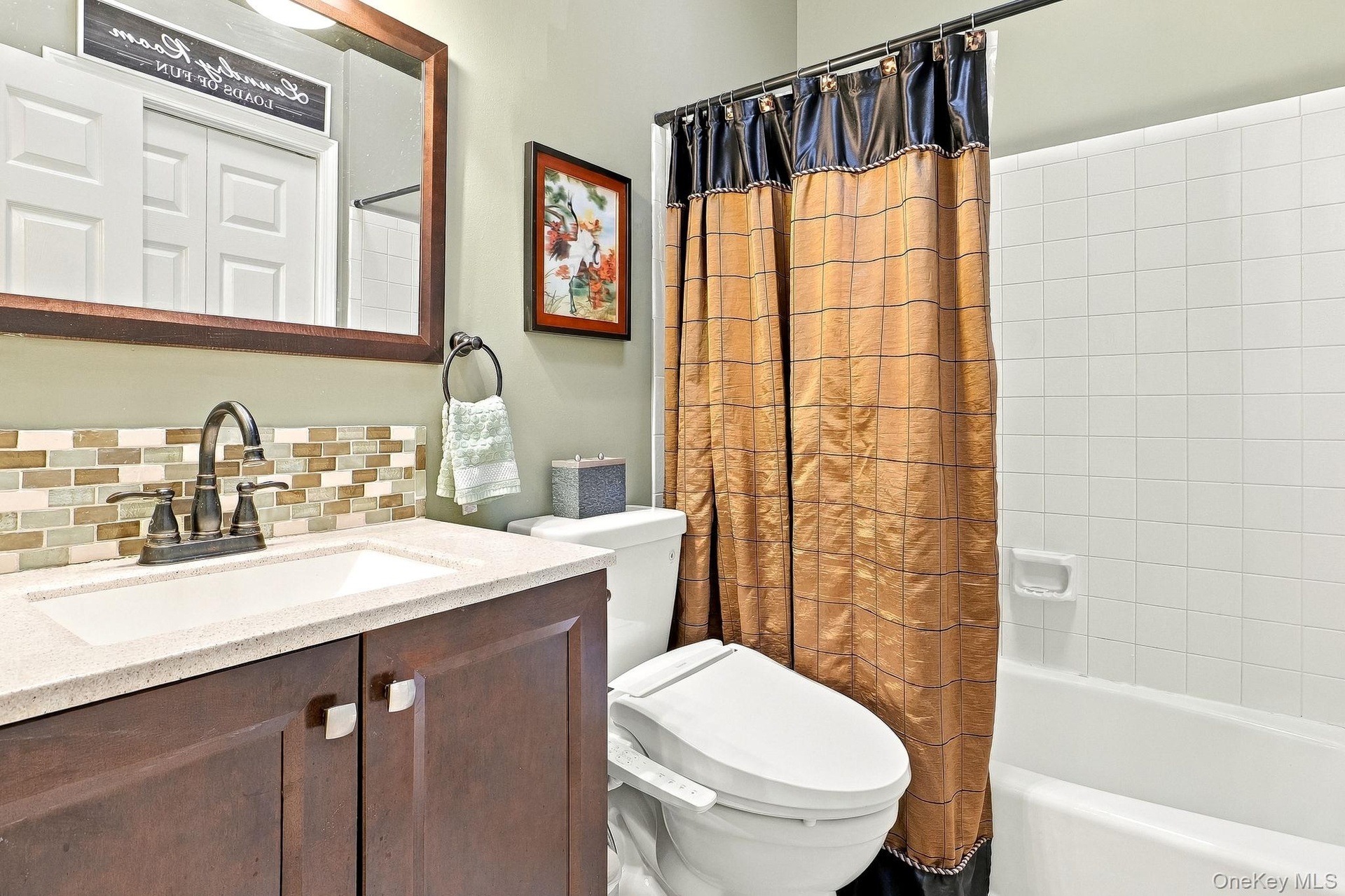 Vanity with a light-countertop, mosaic tile backsplash, and dark wood-finish cabinetry