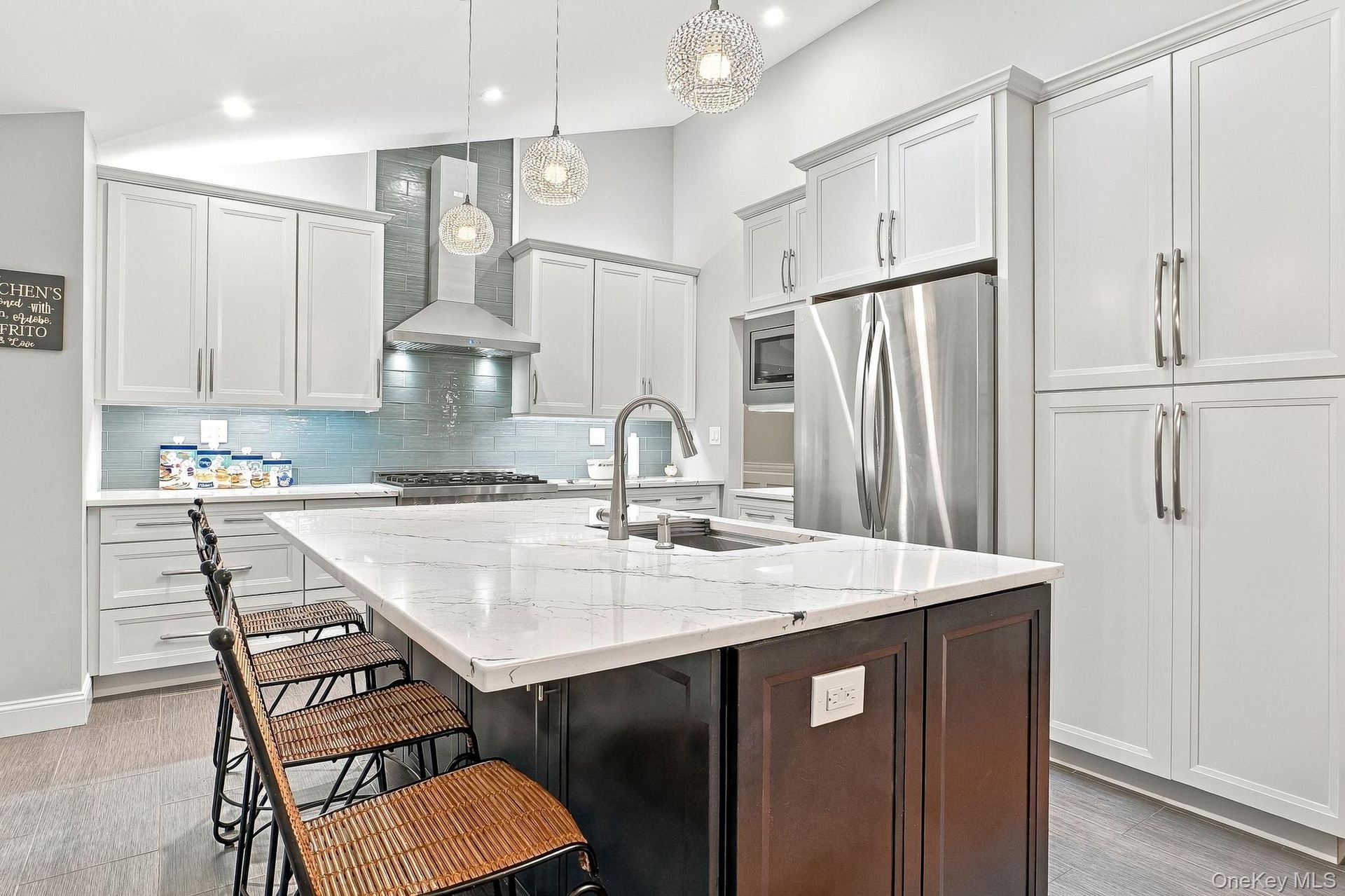 Kitchen featuring a central island with a Quartz countertop, white shaker cabinetry, stainless steel appliances, and a tile backsplash