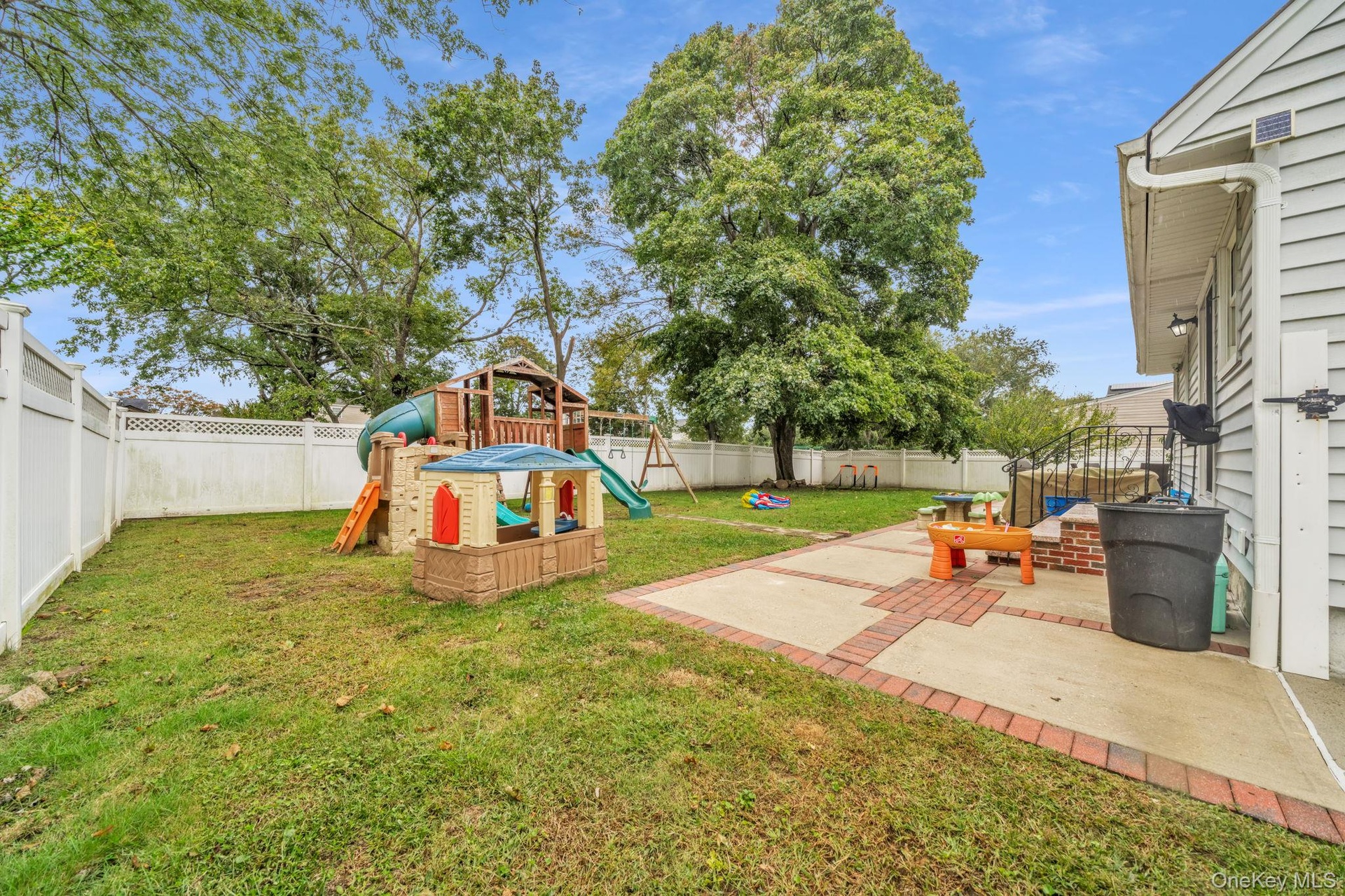Outdoor patio with brick accents and a fenced yard