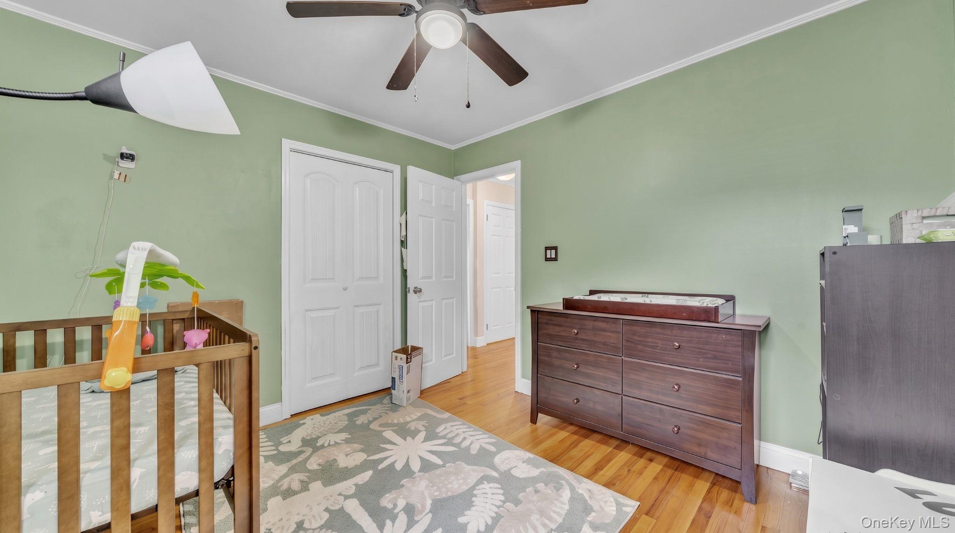 Wood-finish flooring, ceiling fan, white bi-fold closet doors, and white trim
