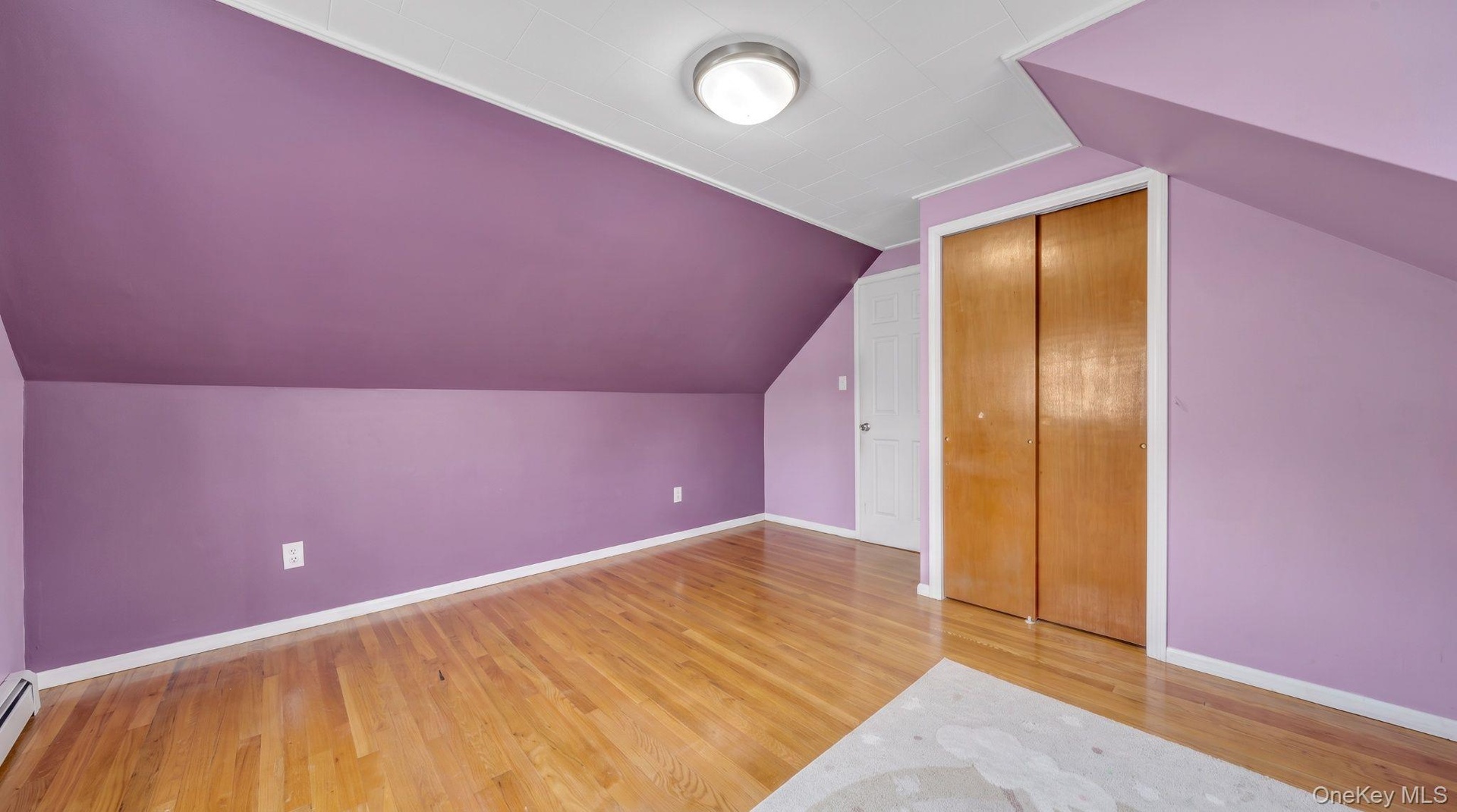 Hardwood flooring, painted walls, built-in closet with bi-fold doors, flush mount ceiling light fixture, and a white door with a round knob