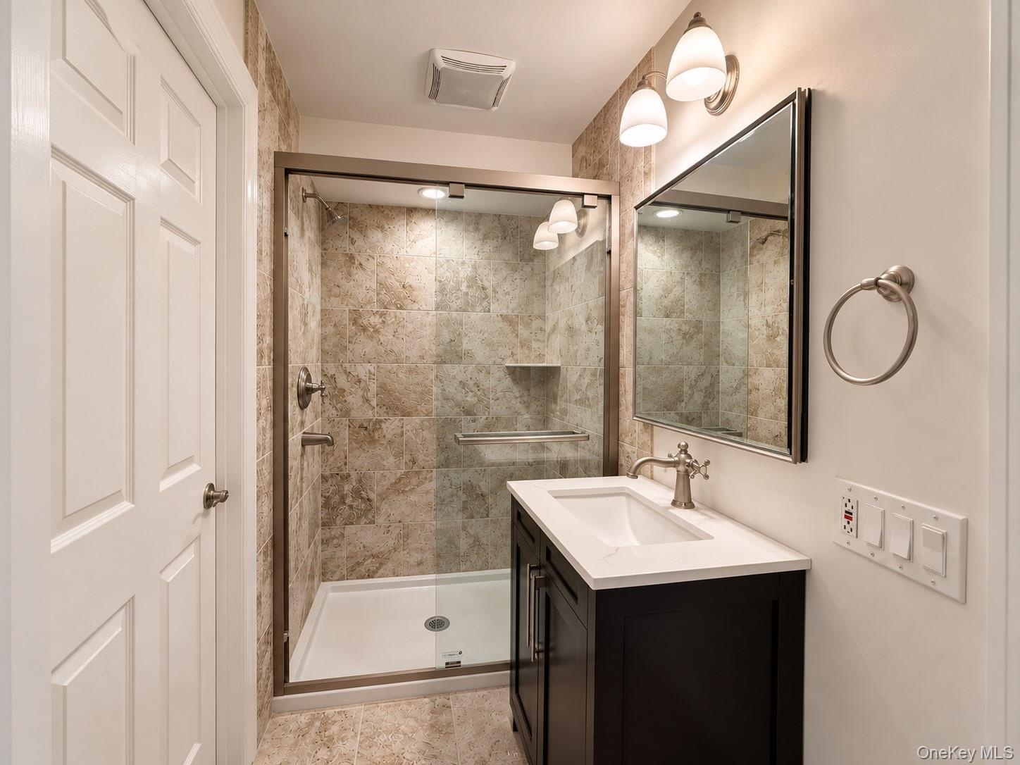 Glass-enclosed shower with tiled walls and a built-in niche