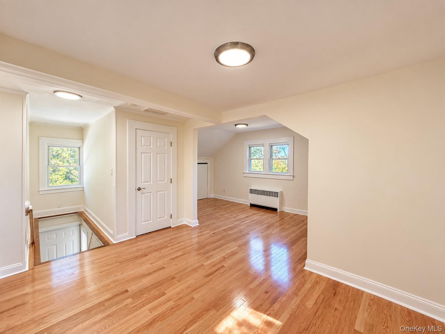 Hardwood flooring, recessed lighting, neutral wall tones, white trim, and white paneled doors