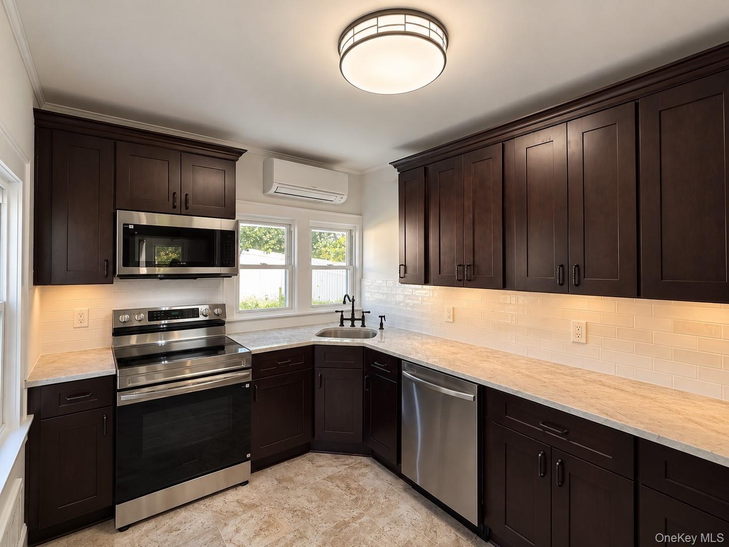 Dark wood-finish cabinetry with crown molding, stainless steel appliances, white subway tile backsplash, light-toned countertops, and a flush mount ce