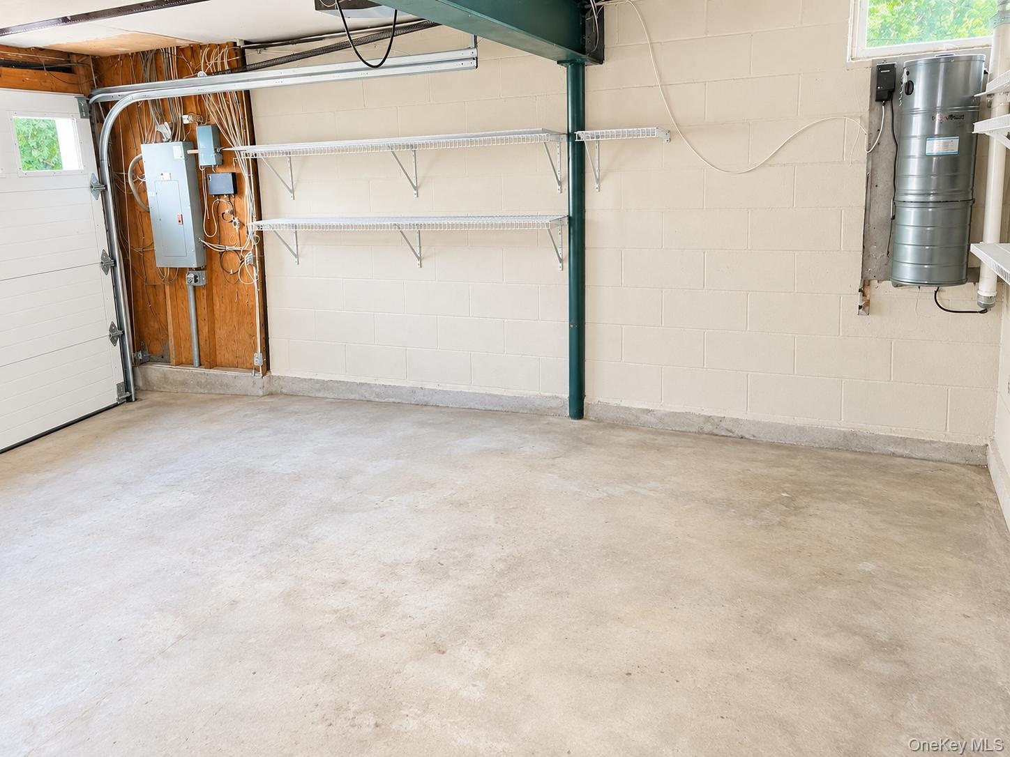Concrete floor, utility shelving, exposed wood framing, white block walls, overhead lighting