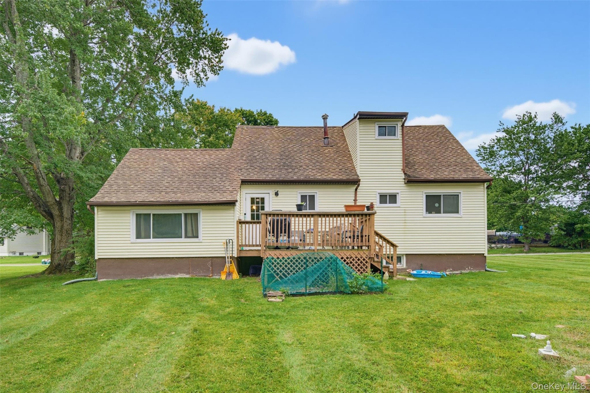 Expansive green lawn with mature trees and a multi-level wood deck