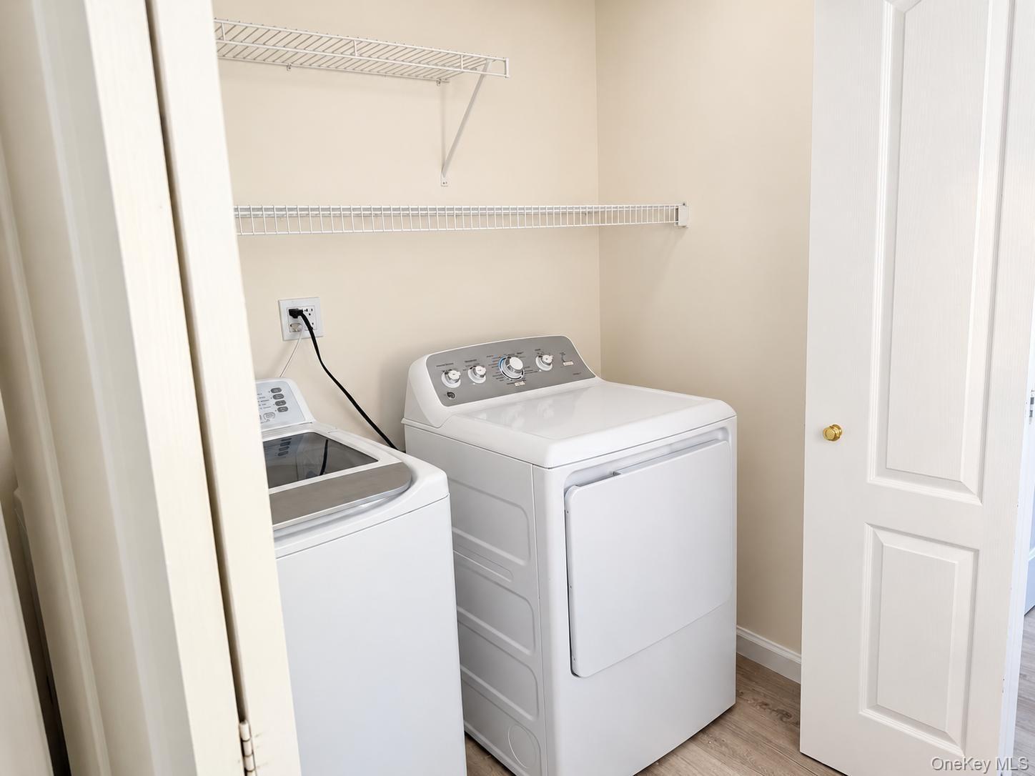 Utility area featuring wire shelving, wood-finish flooring, and a paneled bifold door