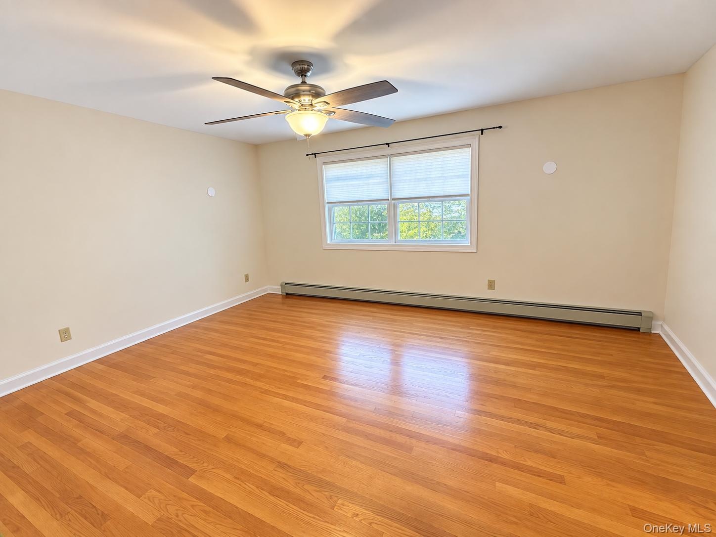 Hardwood flooring, white window trim, ceiling fan with integrated lighting, baseboard heating unit