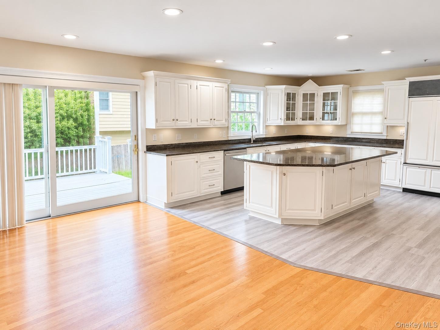 Open-concept kitchen with white cabinetry, dark countertops, and a large central island