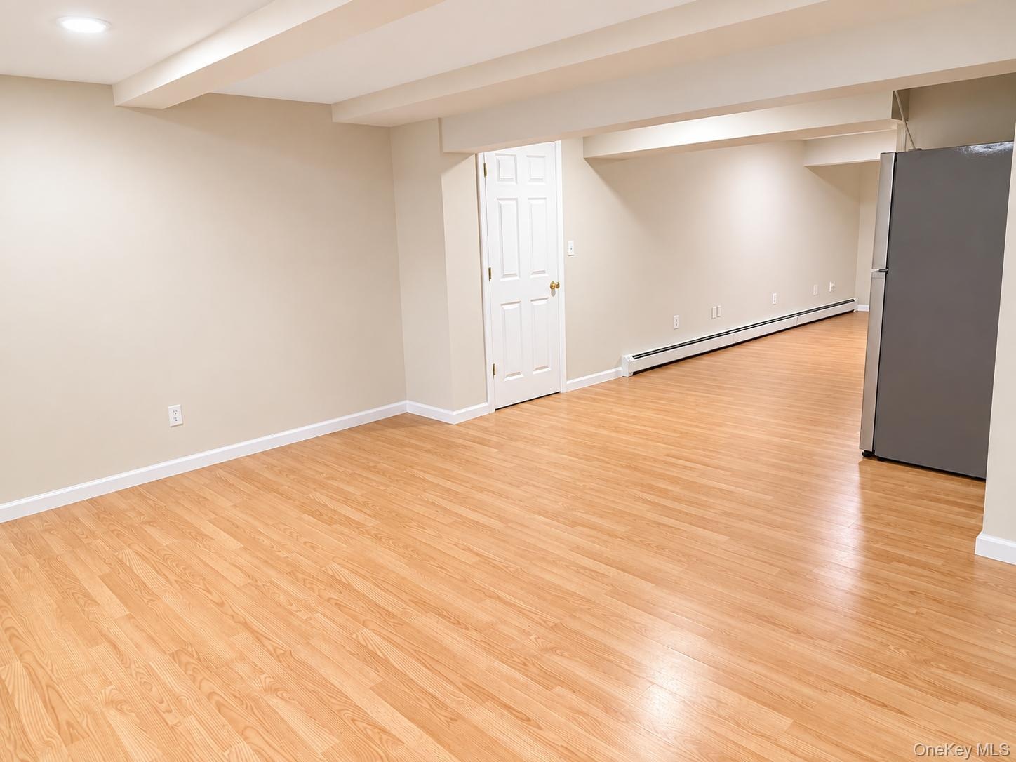 Spacious open-concept room with wood-finish flooring, white trim, and a white paneled door