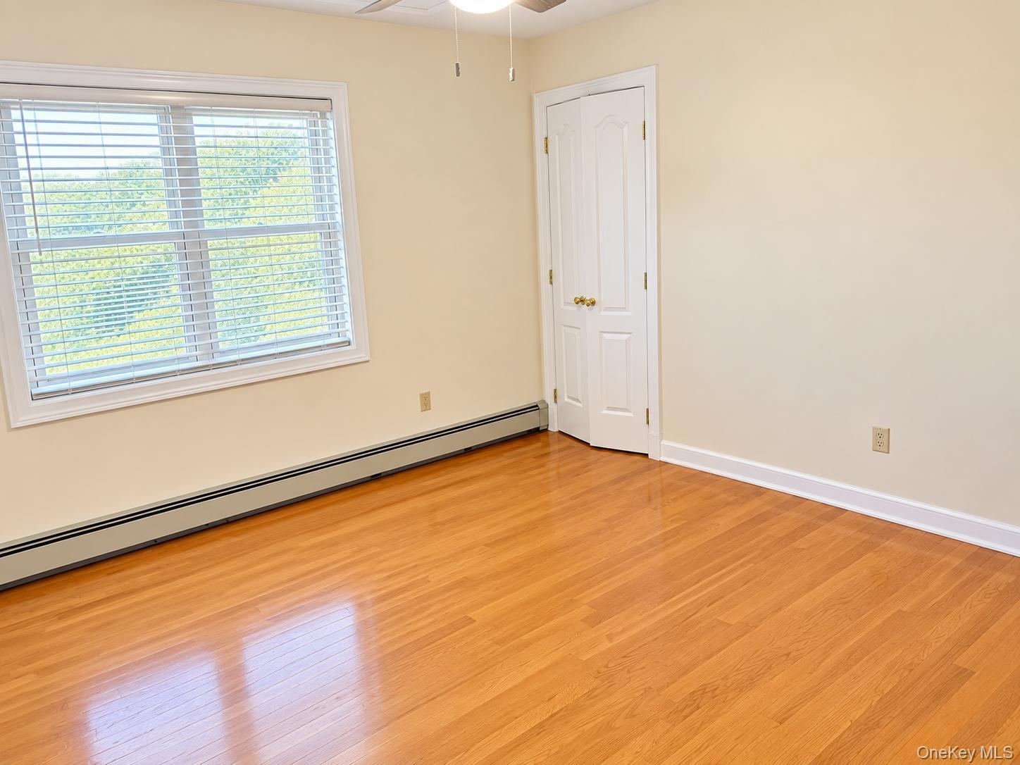 Hardwood flooring, white trim, bifold doors, window with horizontal blinds, and a ceiling fan
