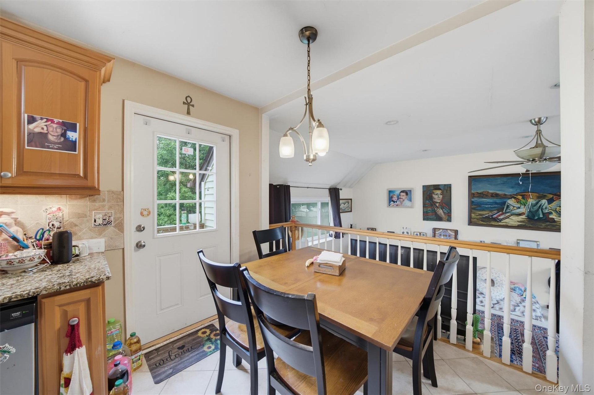 Dining area featuring wood-finish cabinetry, granite-style countertops, and a tiled backsplash