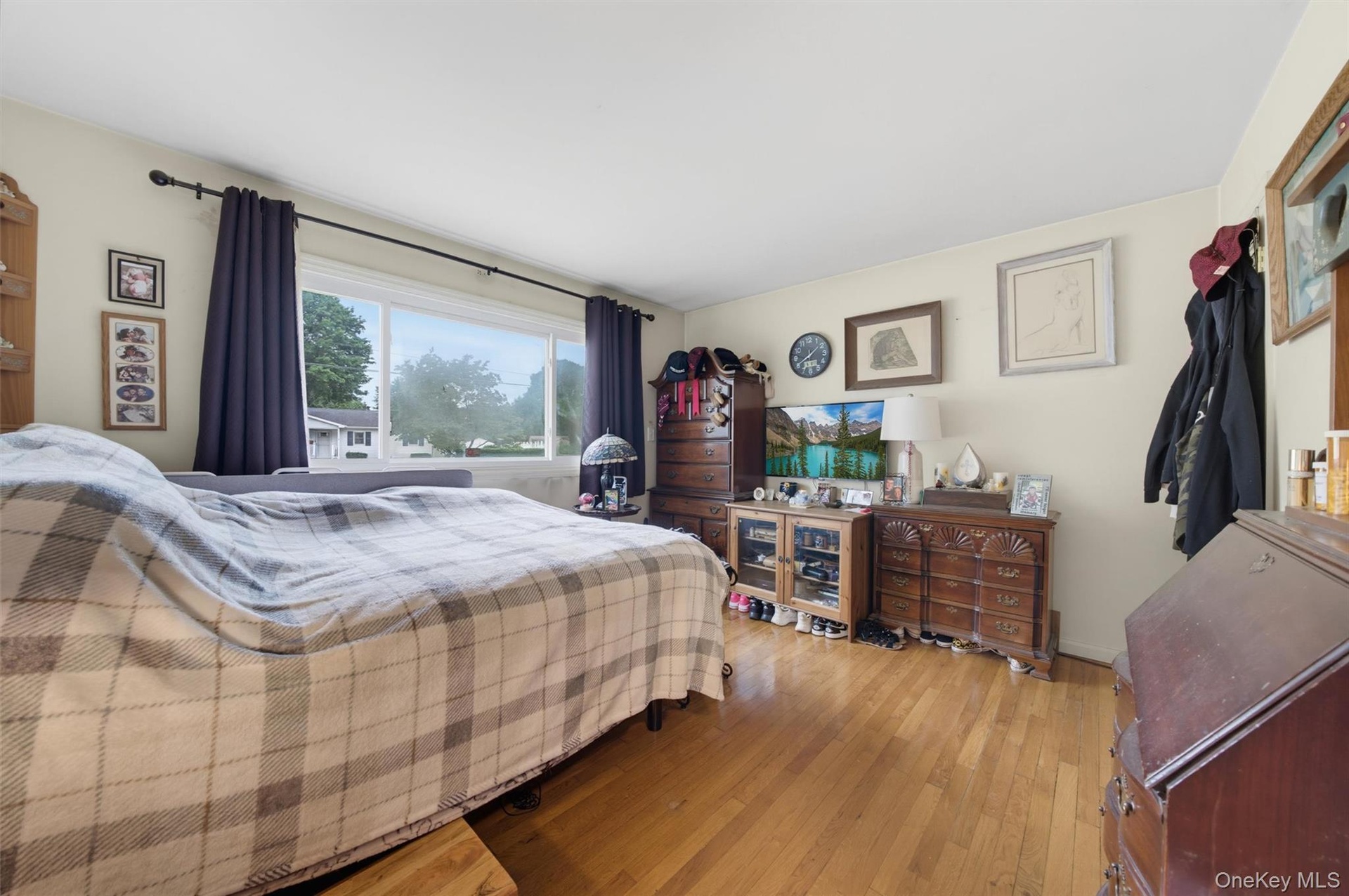 Wood-finish flooring with a large window featuring dark curtains