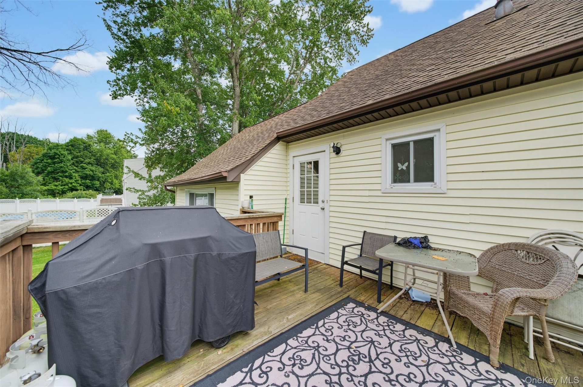 Expansive outdoor deck featuring wood flooring, fencing, and a light-colored siding exterior