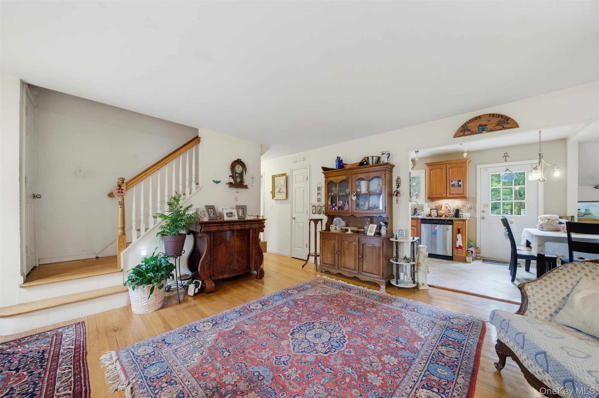 Hardwood flooring, painted white walls, and a wood staircase with white balusters