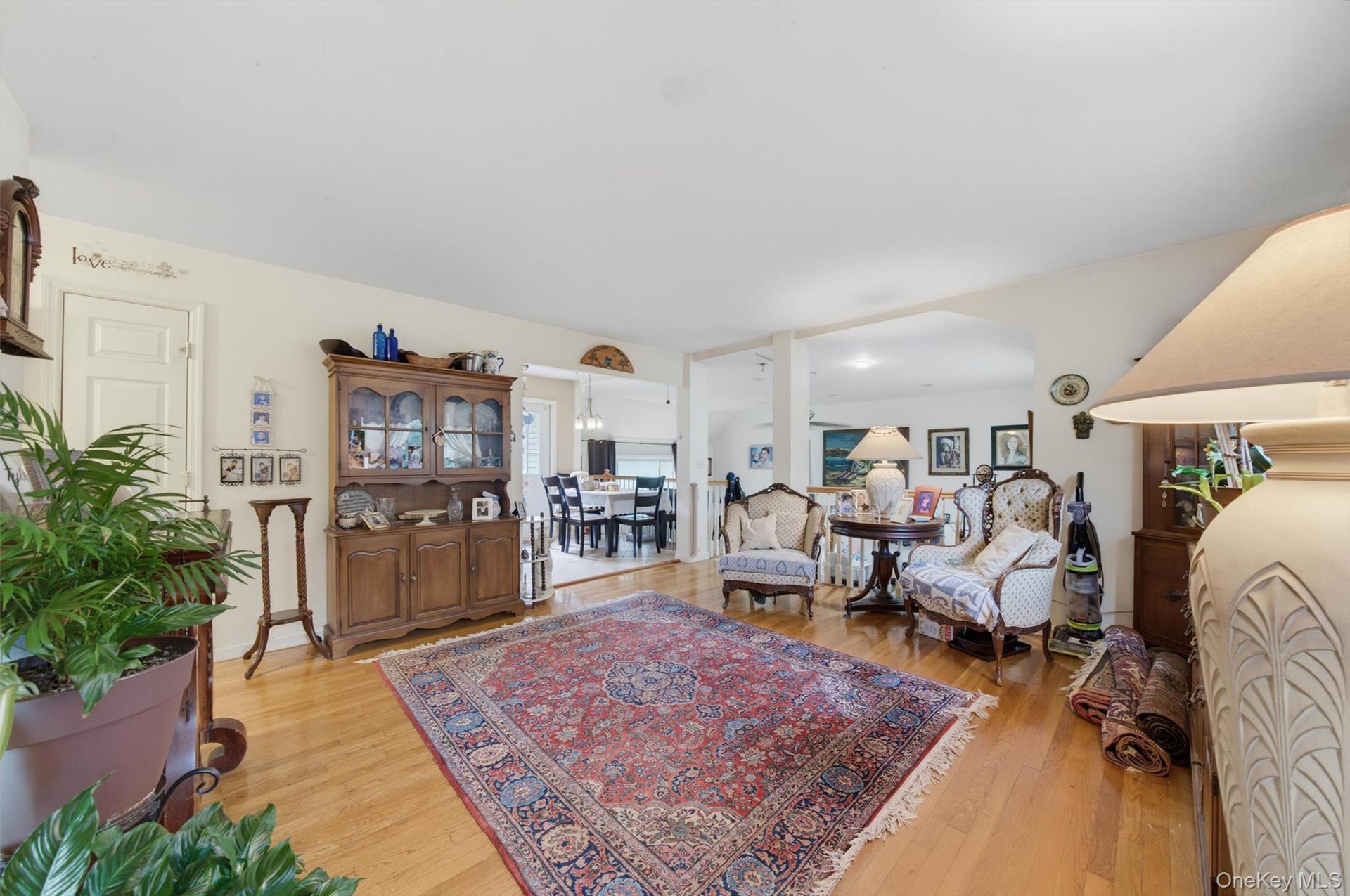Wood-finish flooring throughout, with a wide opening leading to a dining area with a chandelier