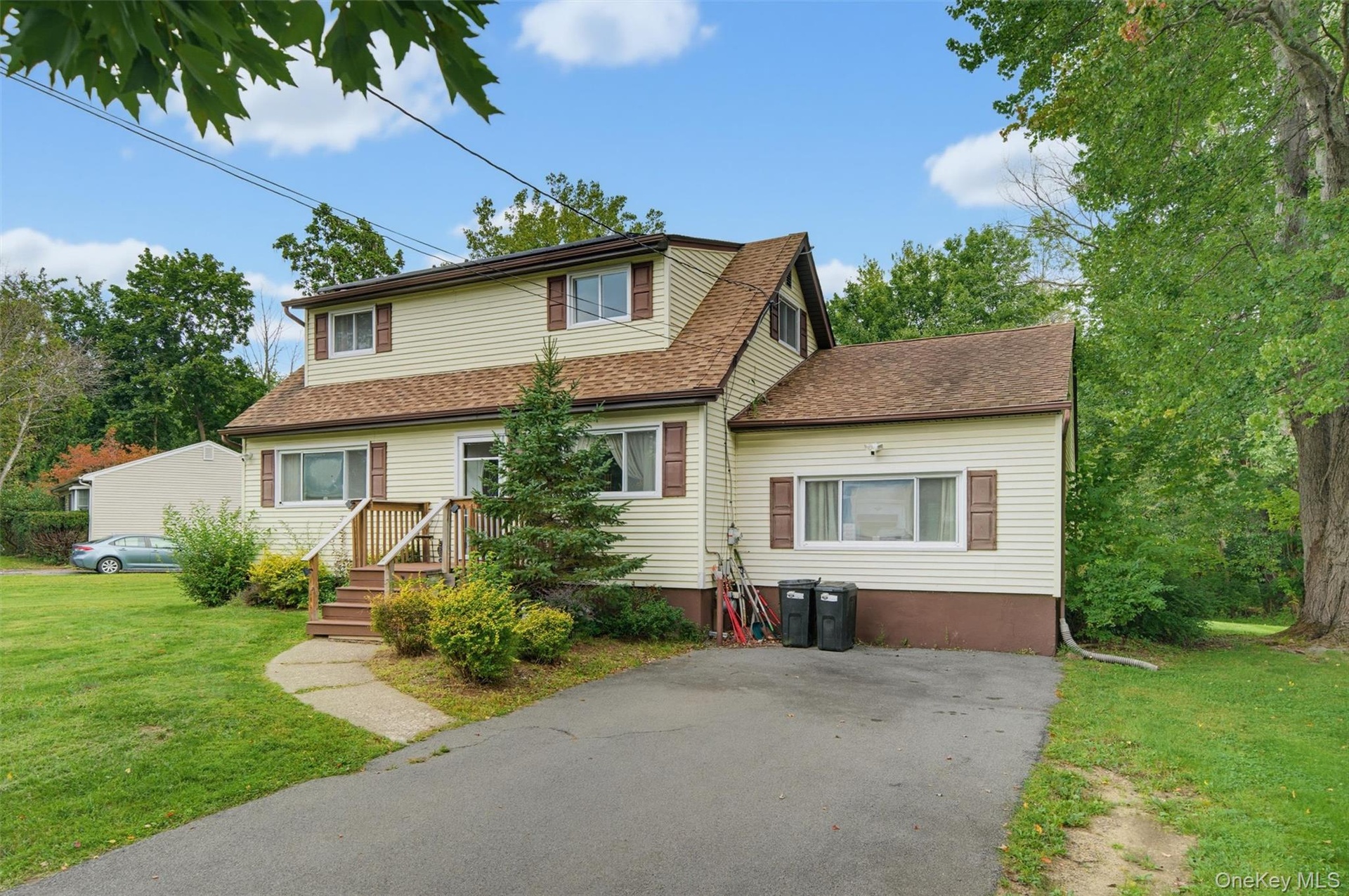 Two-story residence featuring light-colored siding, contrasting brown shutters, and a multi-pitch roof