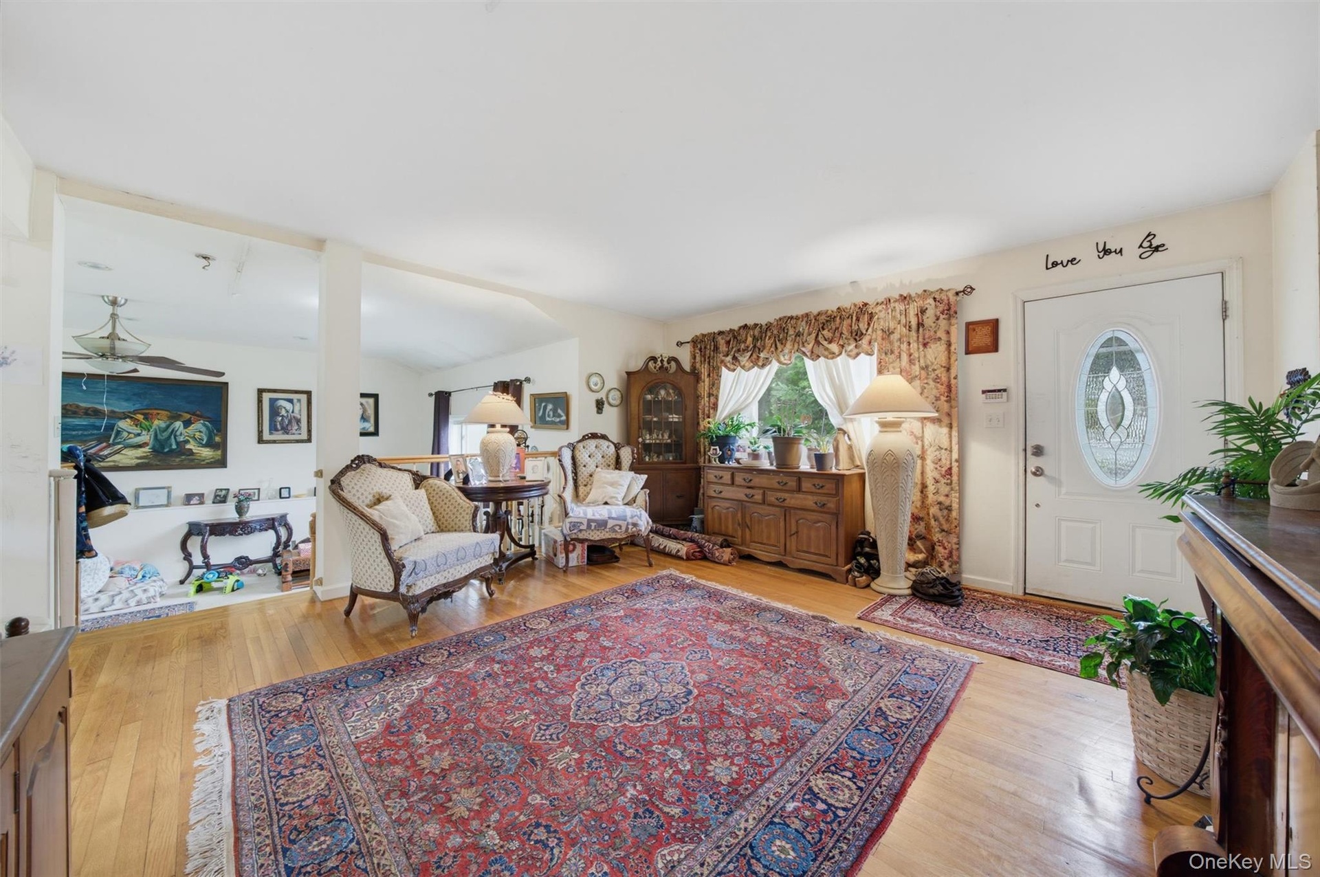 Hardwood-style flooring throughout, an oval-paneled entry door, and a built-in wood-finish cabinet