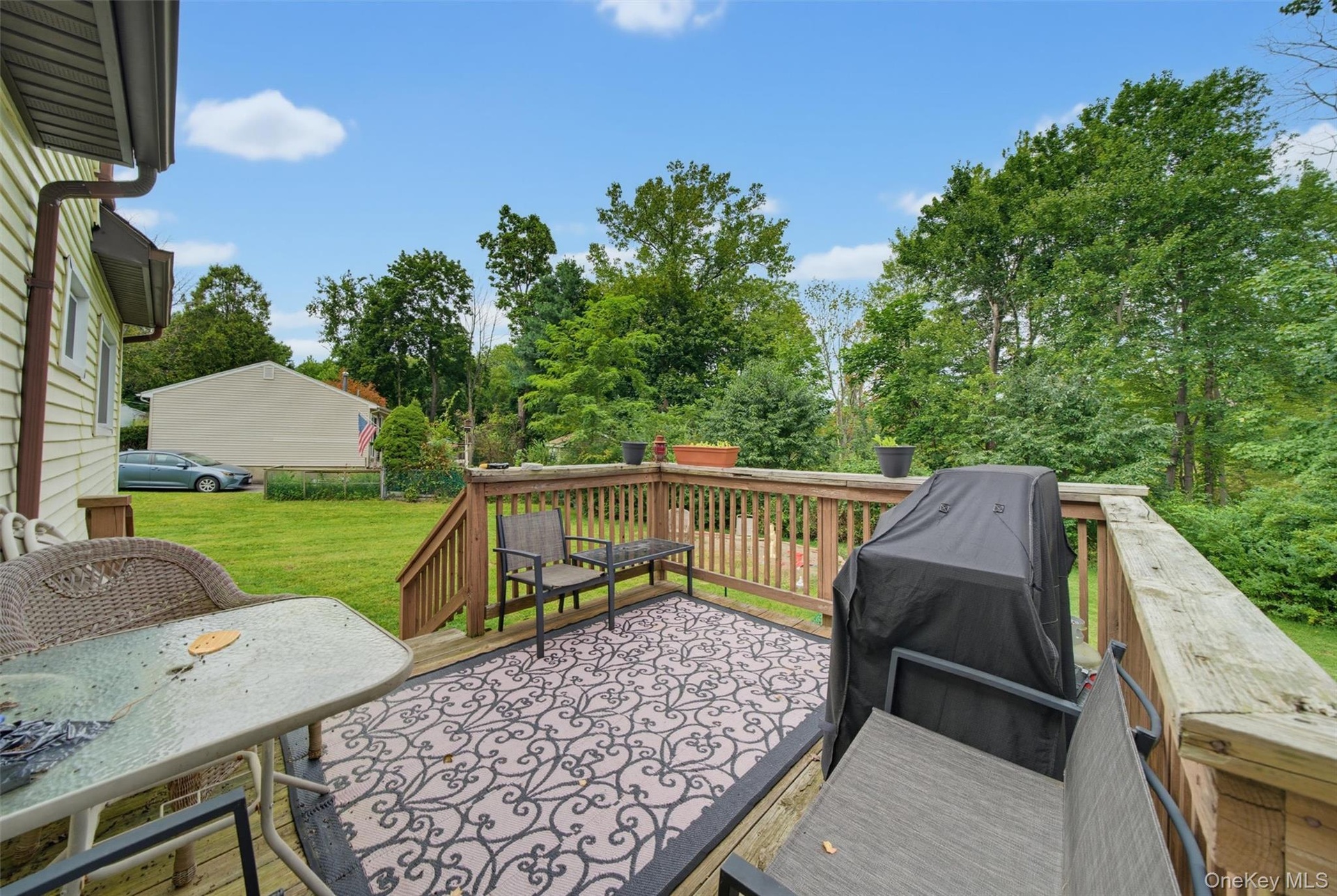 Expansive wood deck with stairs, featuring wood railings and a green yard