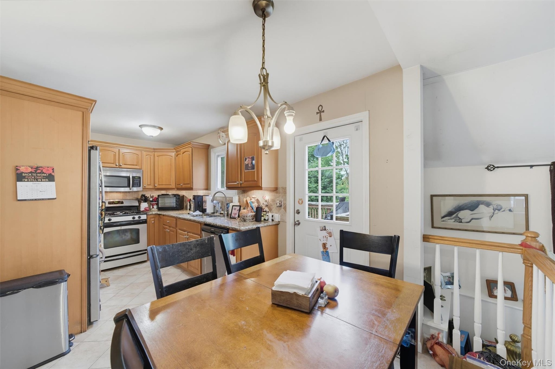 Kitchen featuring light wood-finish cabinetry, stainless steel appliances, and tiled flooring