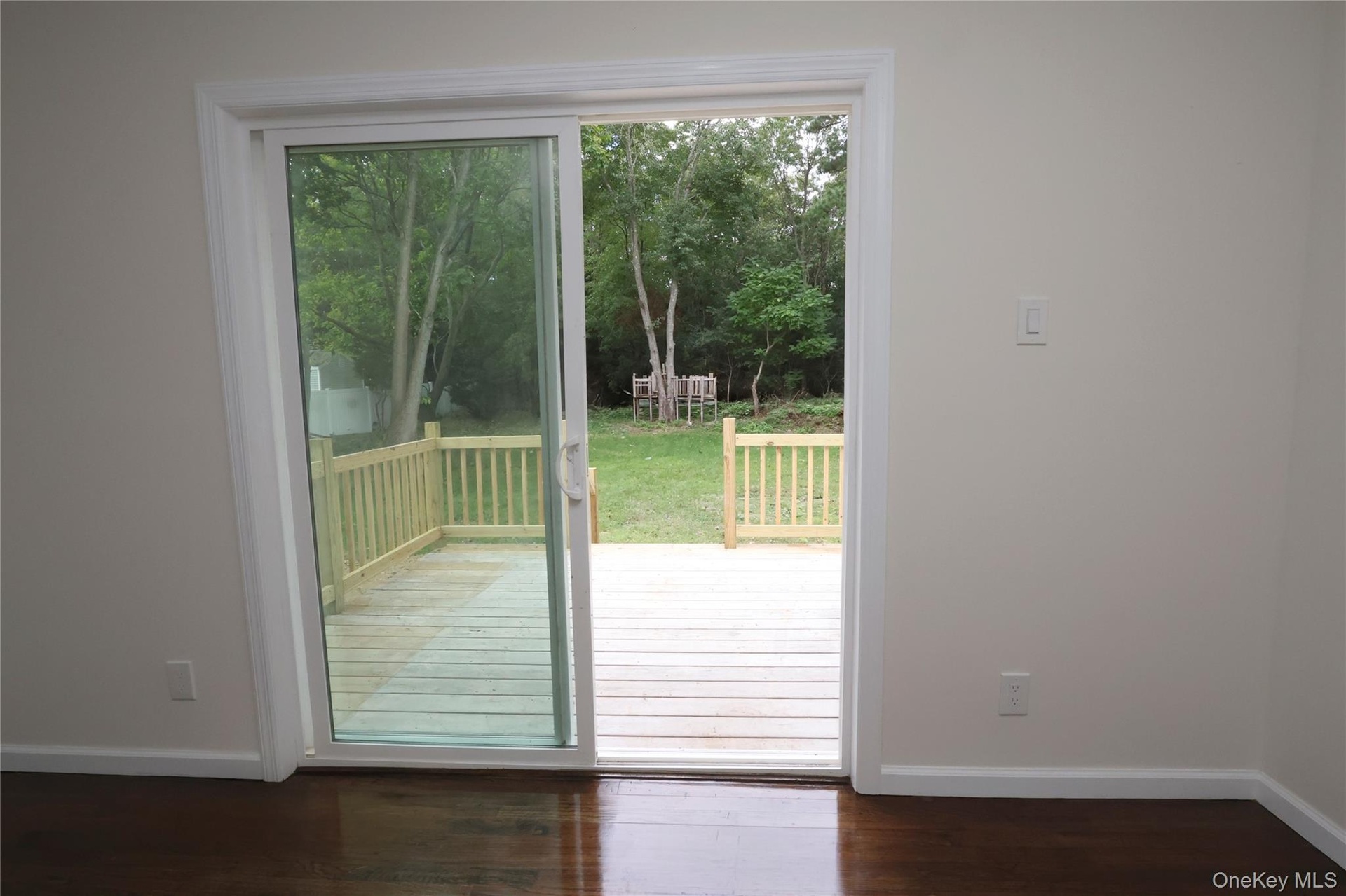 Hardwood-finish flooring, light-toned walls, and a sliding glass door opening to a wooden deck
