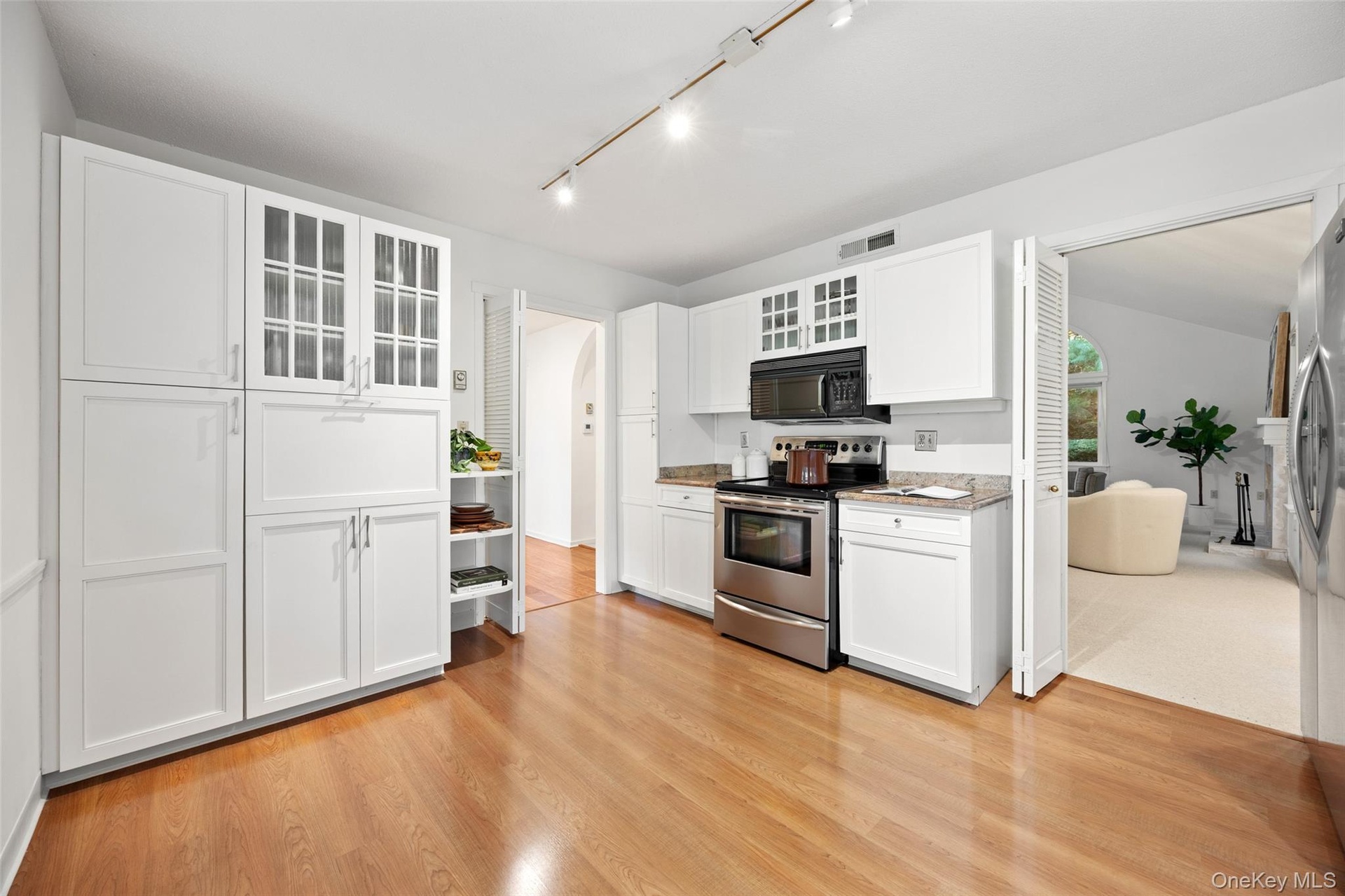 Charming white kitchen with granite countertops, stainless steel appliances, and abundant storage - plenty of room to add a breakfast table for casual