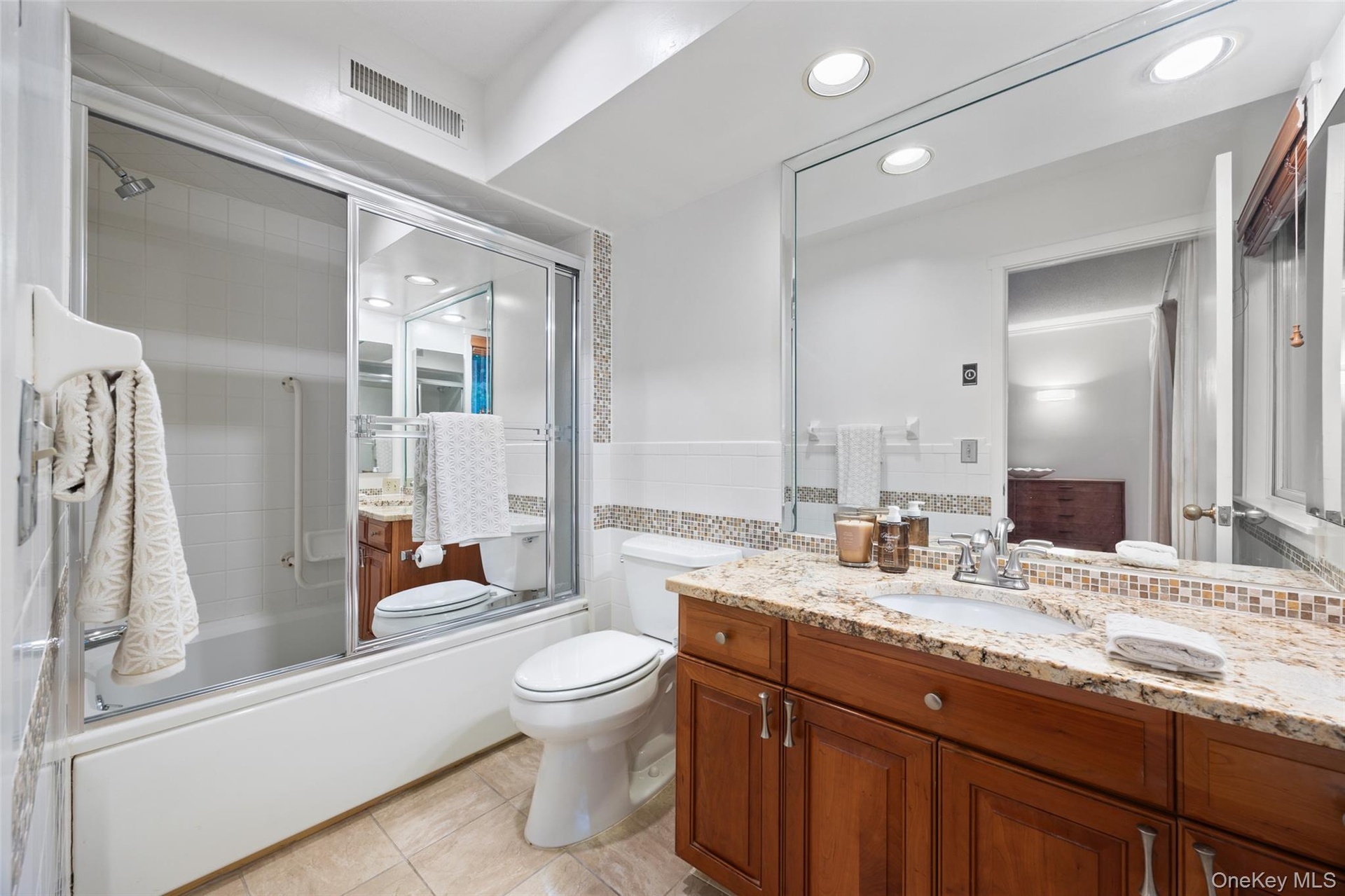 Ensuite primary bathroom with granite-top vanity.